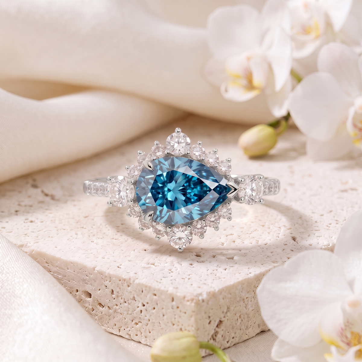 Pear cut blue moissanite sunburst halo engagement ring in white gold.