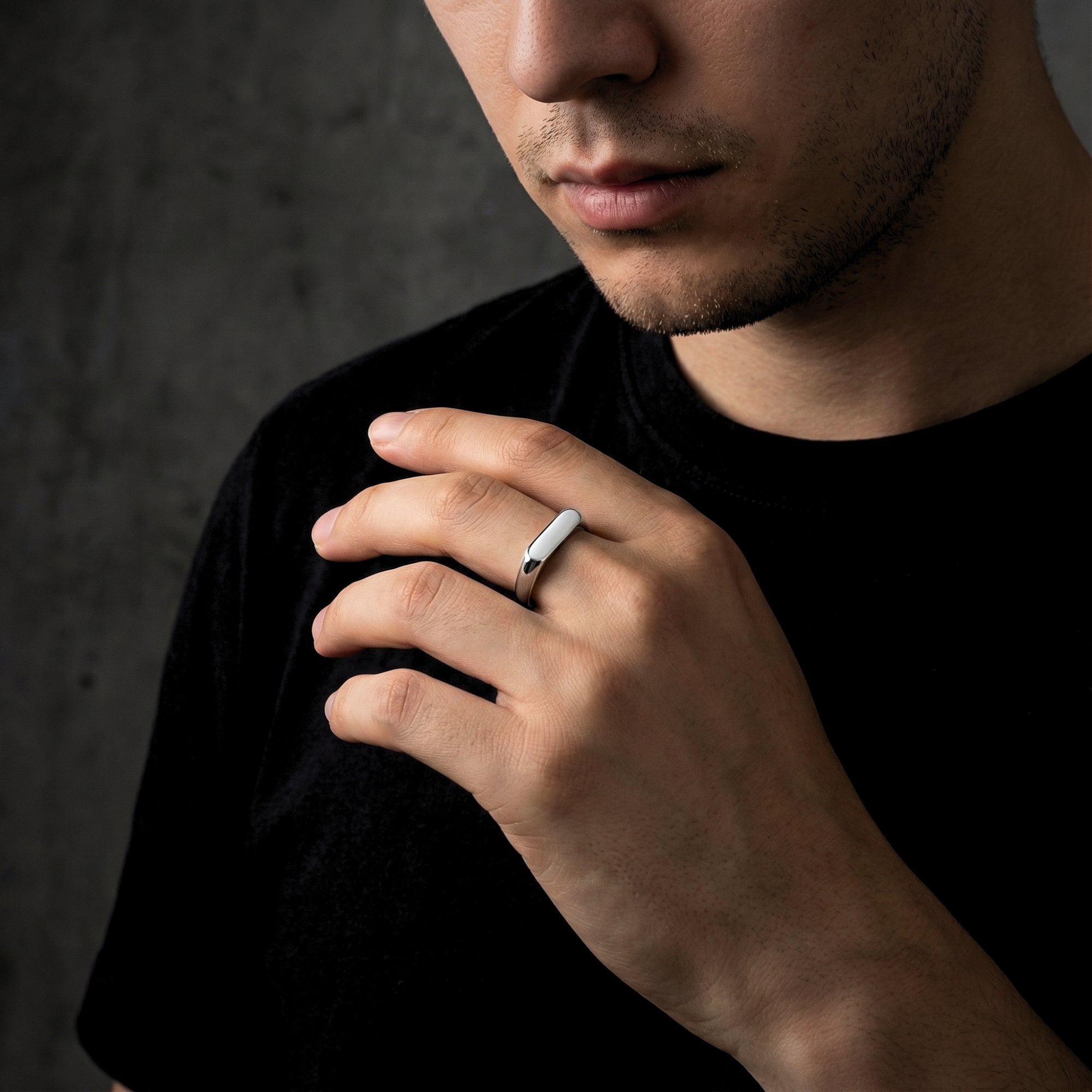 Modern minimalist silver signet ring for men shown on a model's hand for style reference.