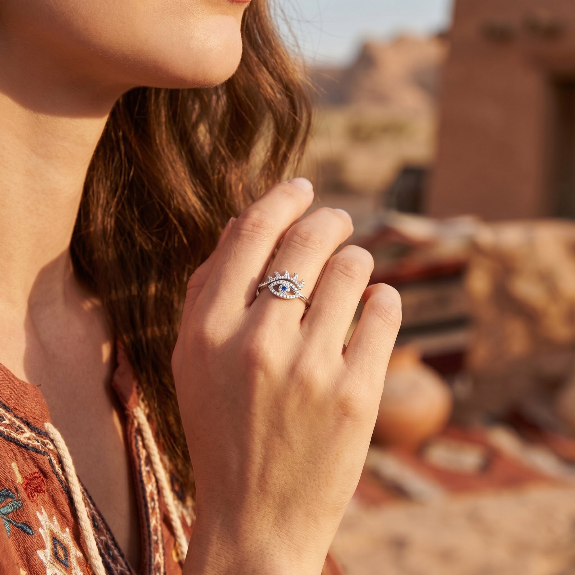 Model wearing the sterling silver eye-shaped ring with a blue center stone against a desert background.