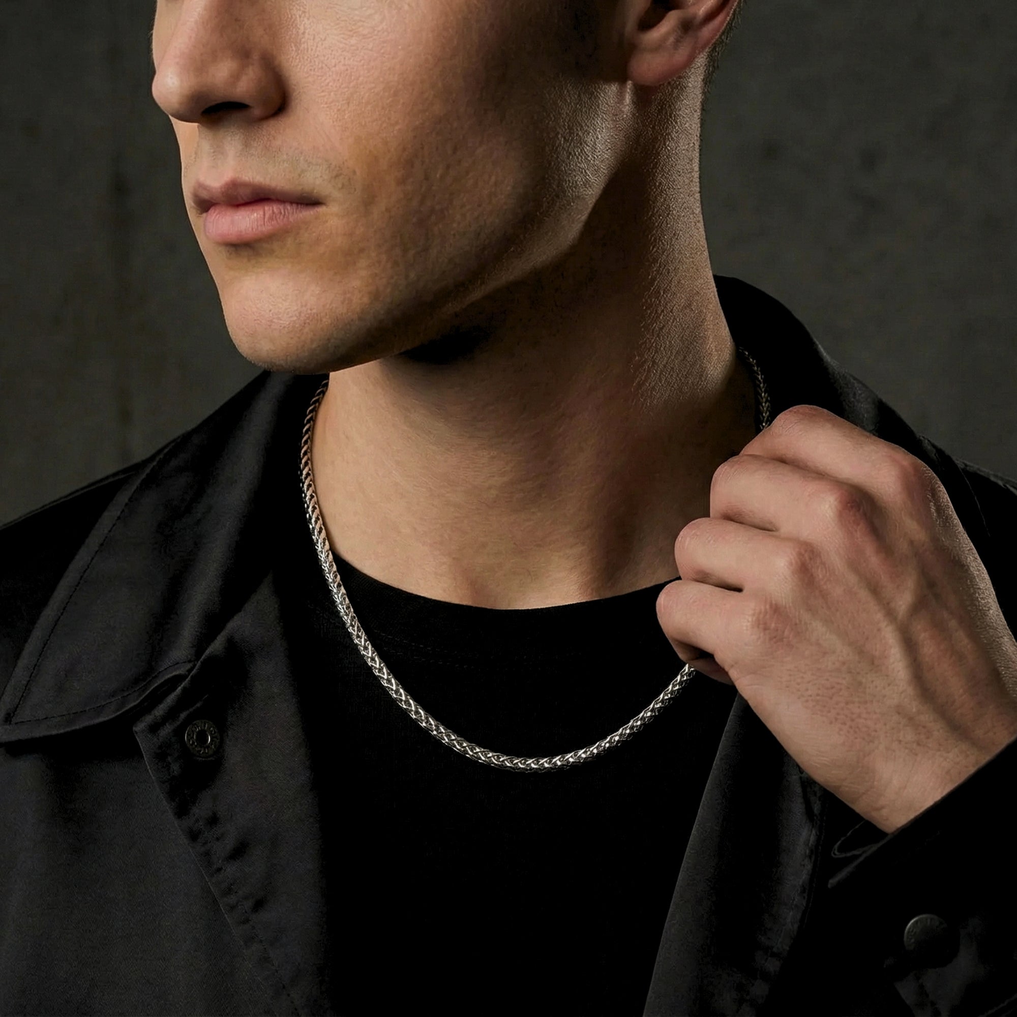 A model wearing a 6mm silver stainless steel wheat chain necklace with a black jacket.