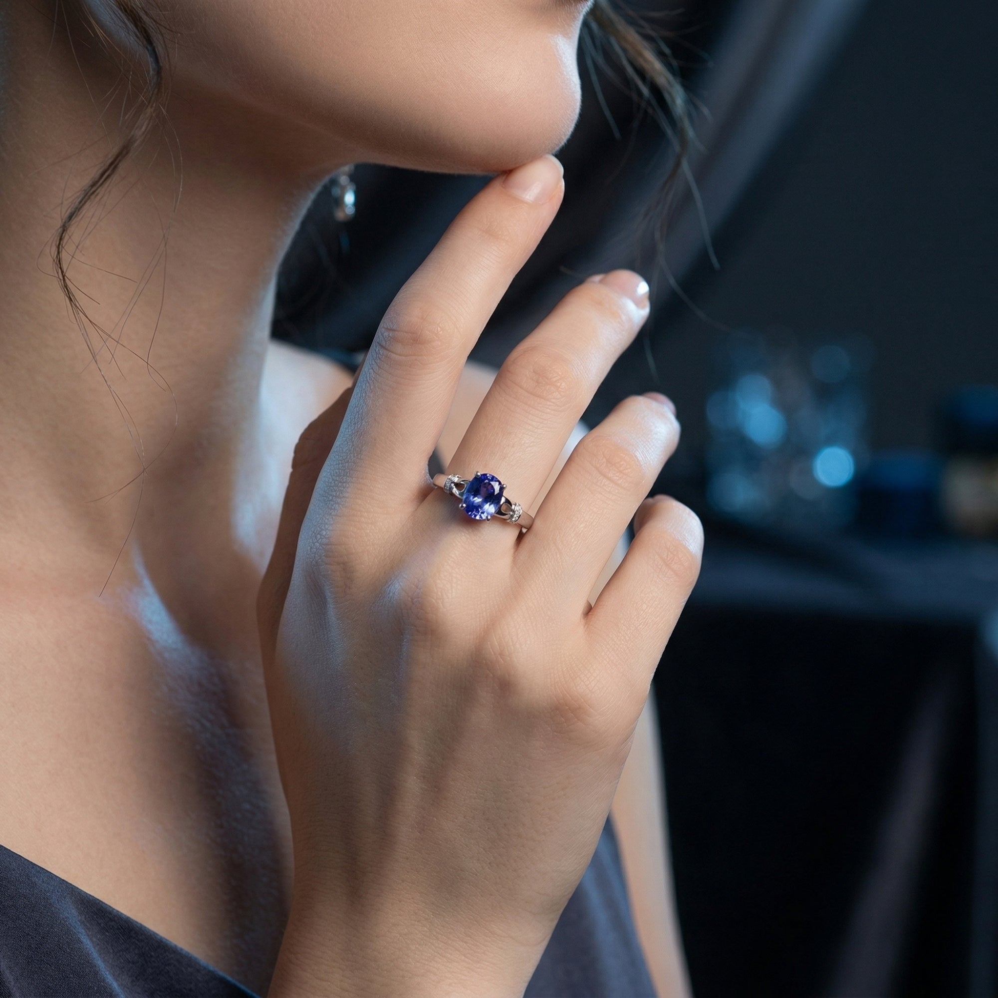 Model wearing the 18K white gold Illiana ring featuring a vivid oval-cut natural tanzanite center stone.