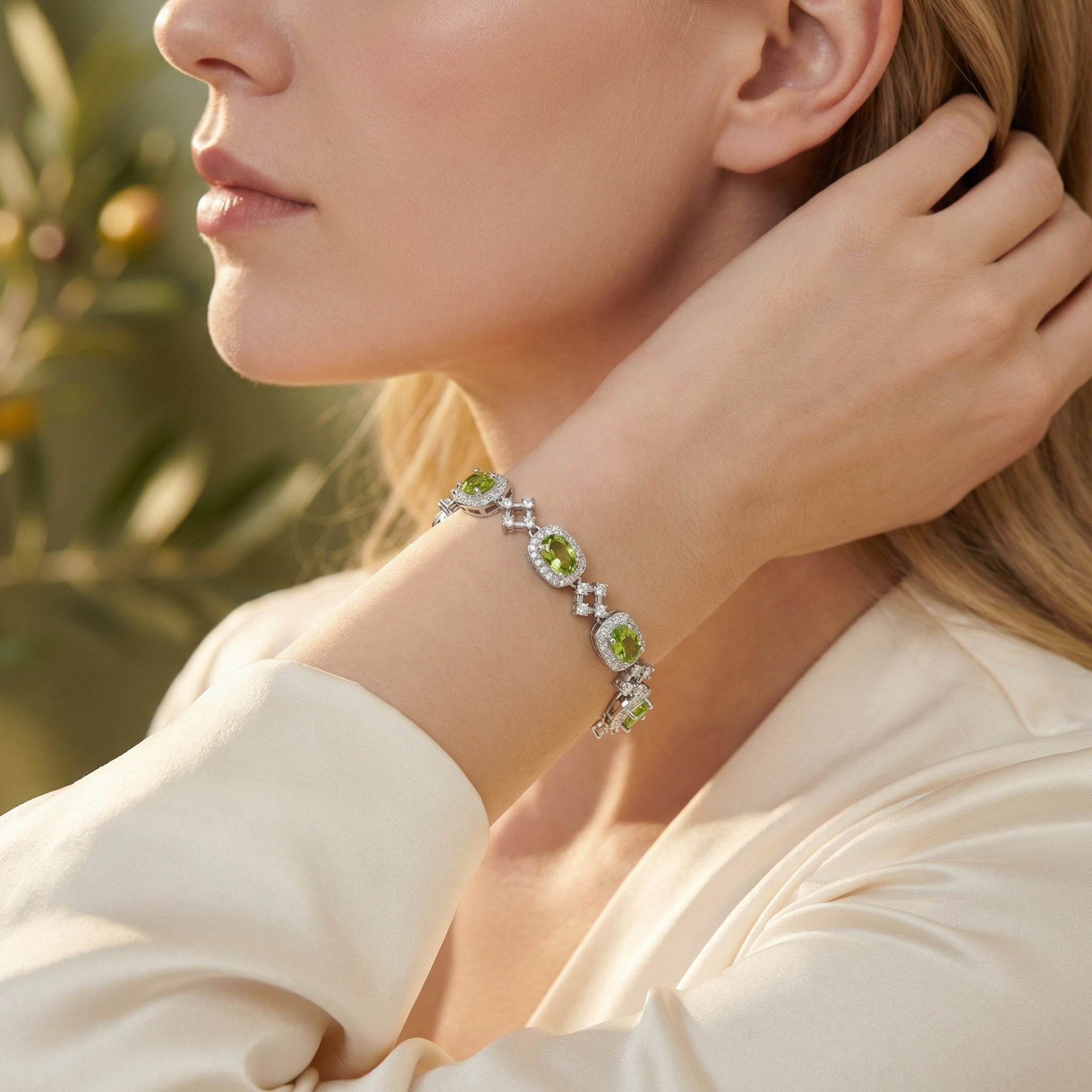 Sterling silver station bracelet with five oval cut peridot gemstones worn by a model in soft lighting.