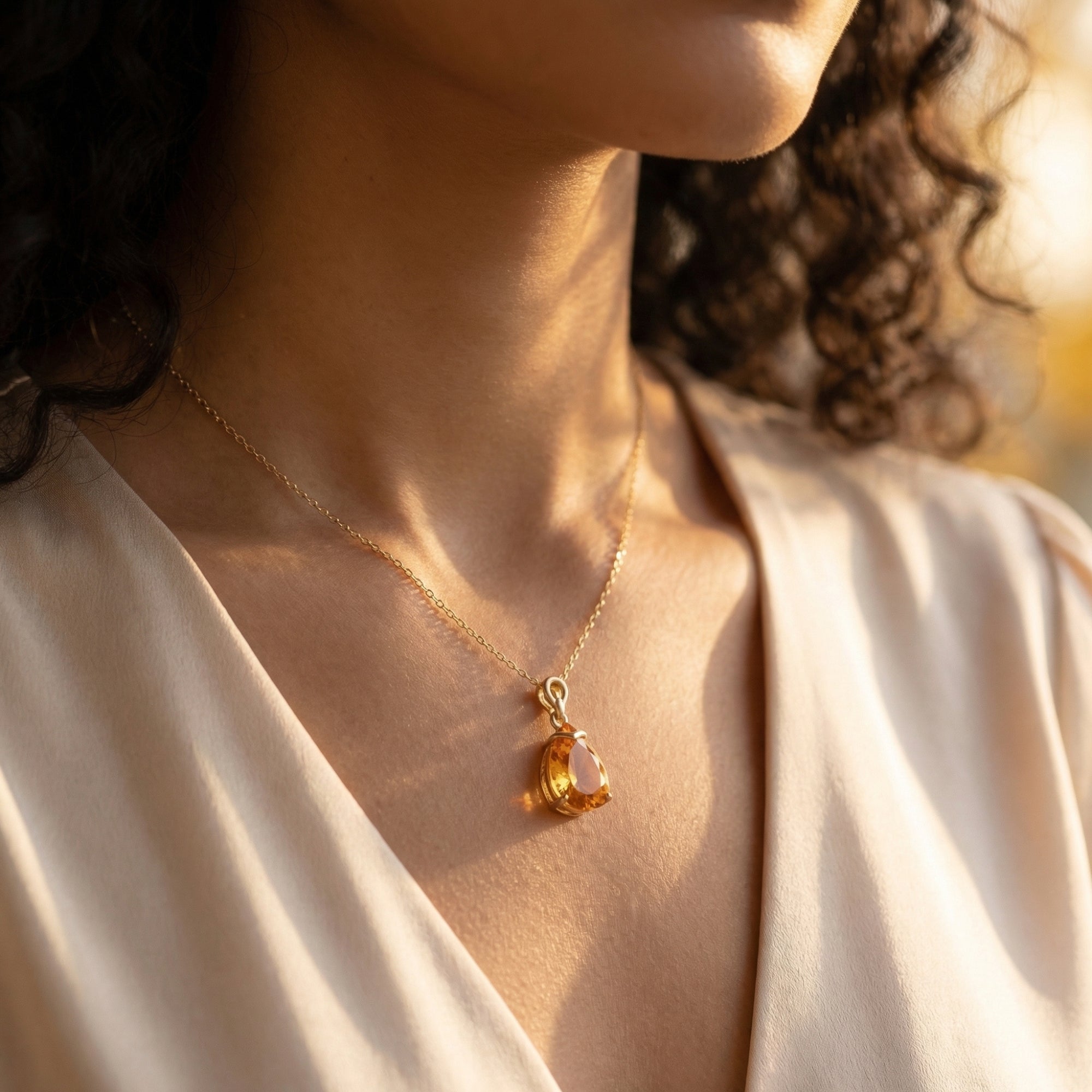 Side view of a model wearing the 18K yellow gold pear-cut citrine necklace in soft natural light.