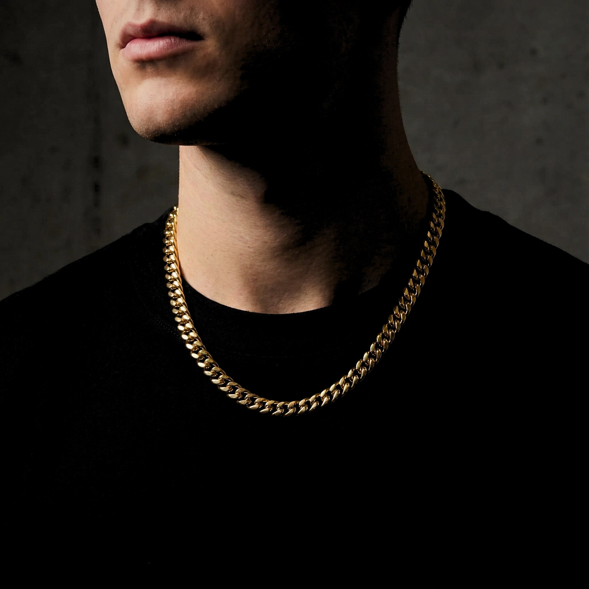 Model wearing the 8mm gold Cuban chain in stainless steel over a black t-shirt.
