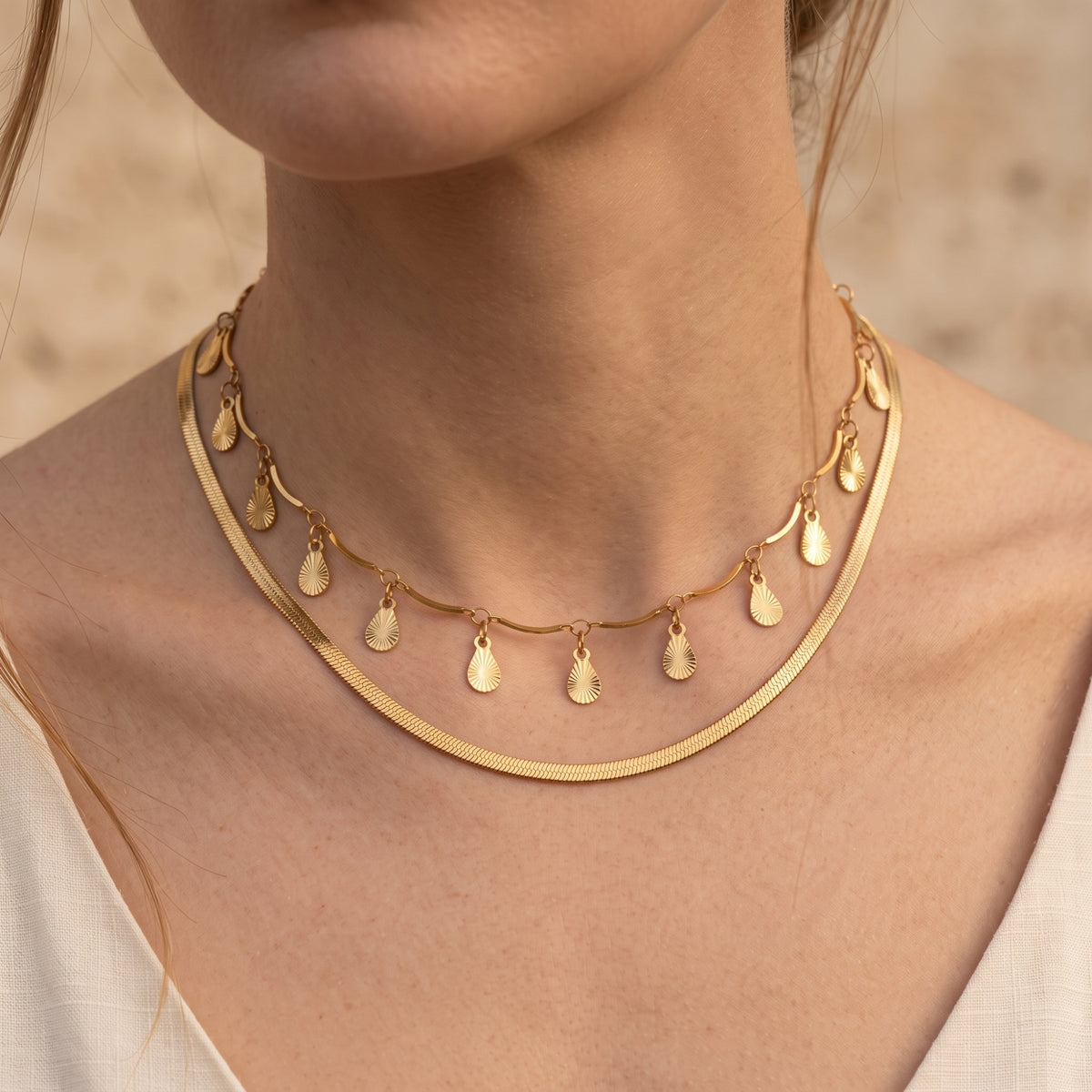 Close-up of the gold-toned layered necklace draped neatly around a model's neck and collarbone.