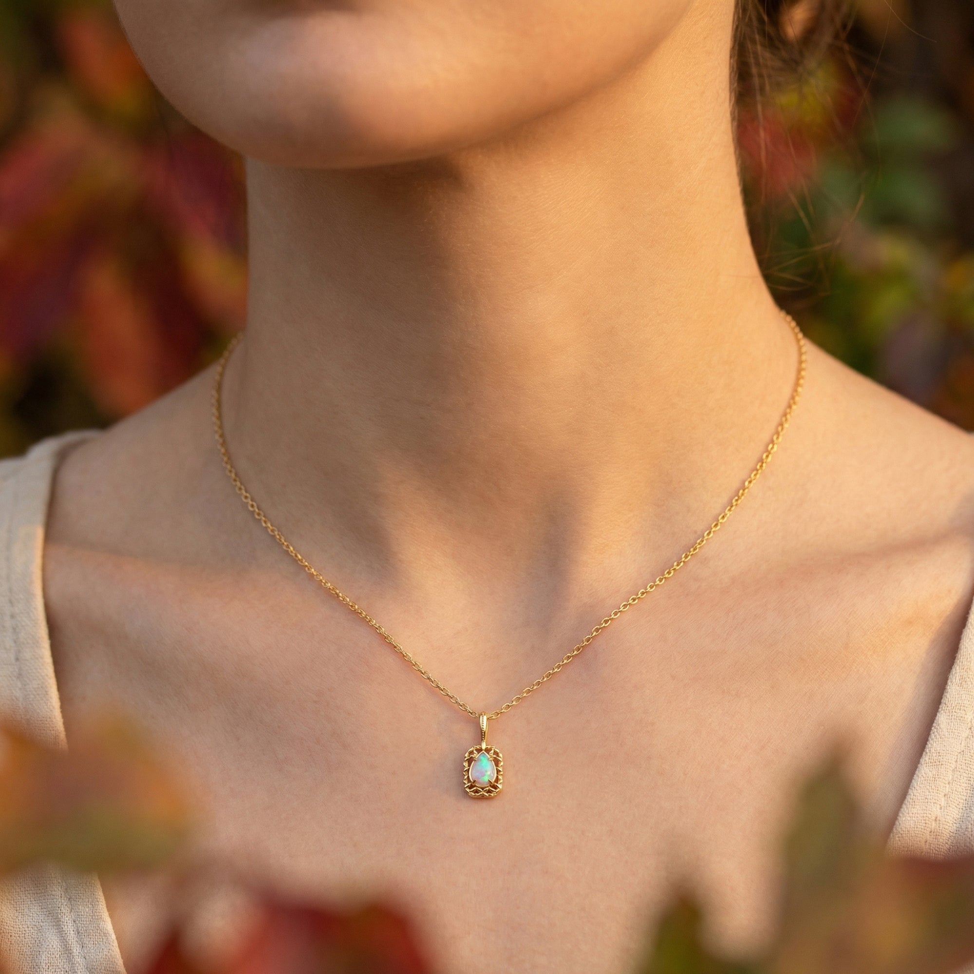 Front view of the Avelina pear-cut opal pendant necklace in gold finish worn by a model.