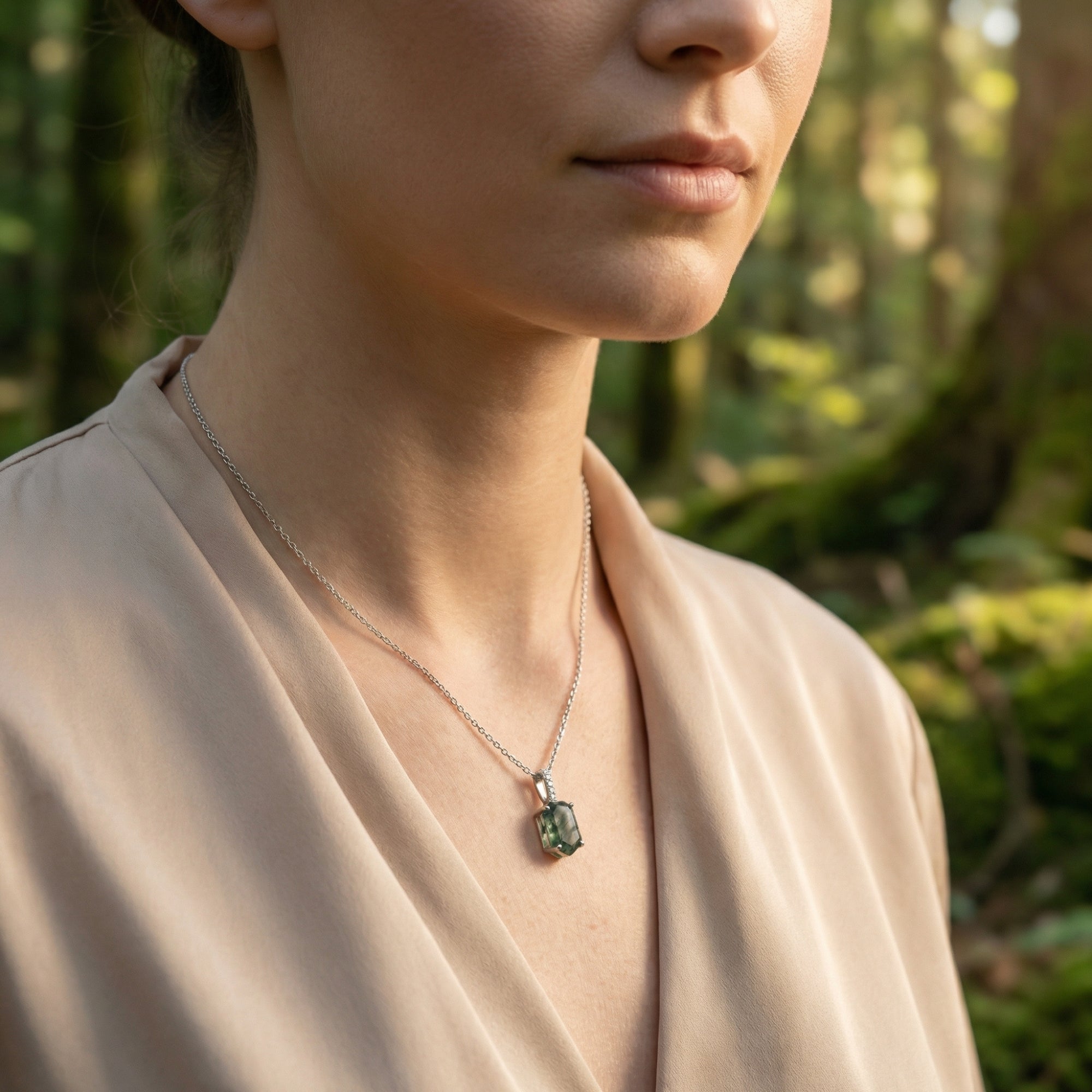 A woman wearing the sterling silver moss agate column necklace outdoors, showcasing the pendant's natural green patterns.