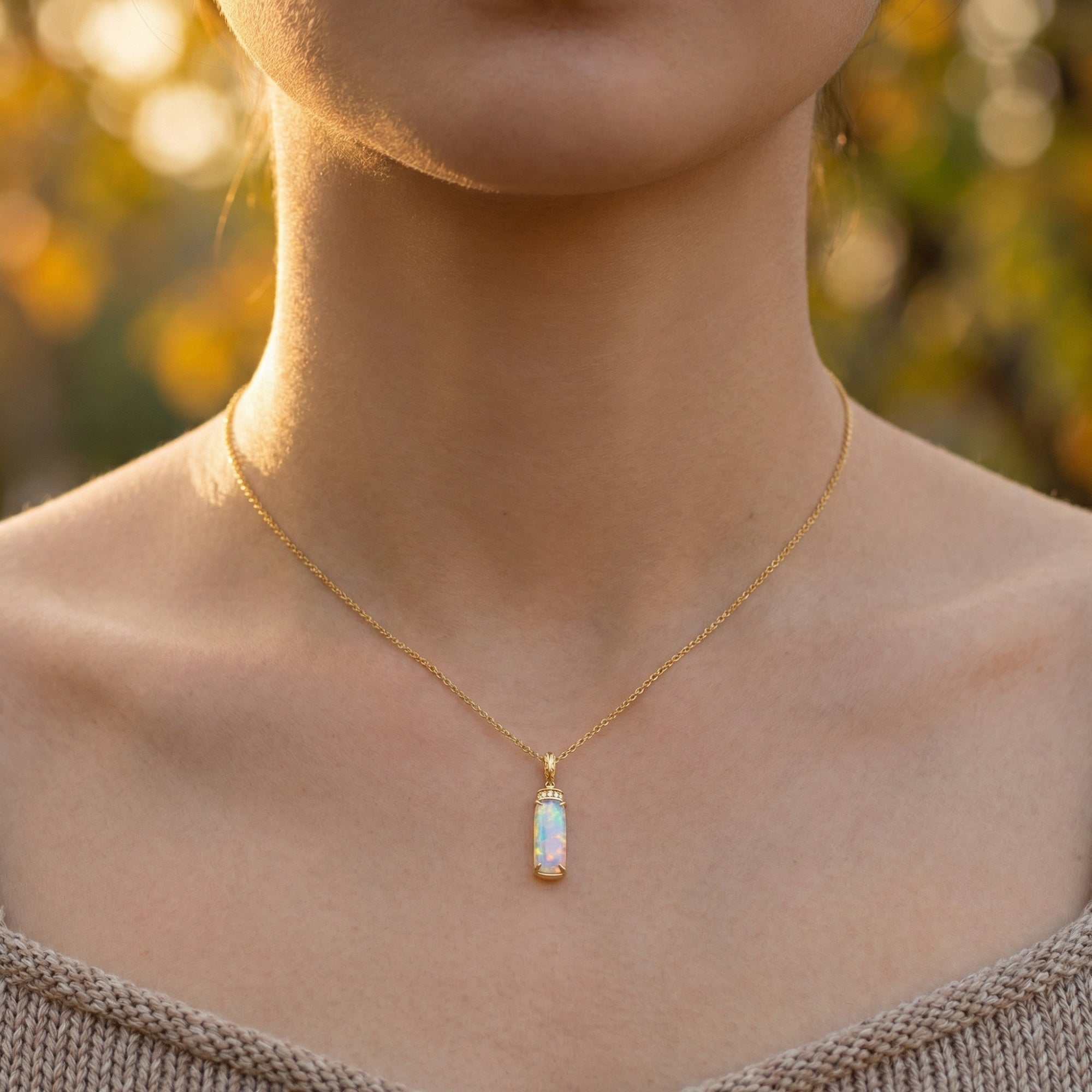 Front view of a model wearing the gold-tone Galatea necklace with a minimalist white opal column pendant.