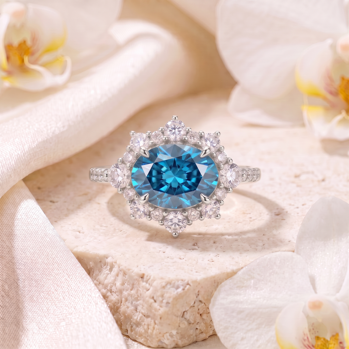 Front view of a white gold engagement ring featuring an oval blue moissanite gemstone surrounded by a diamond halo.