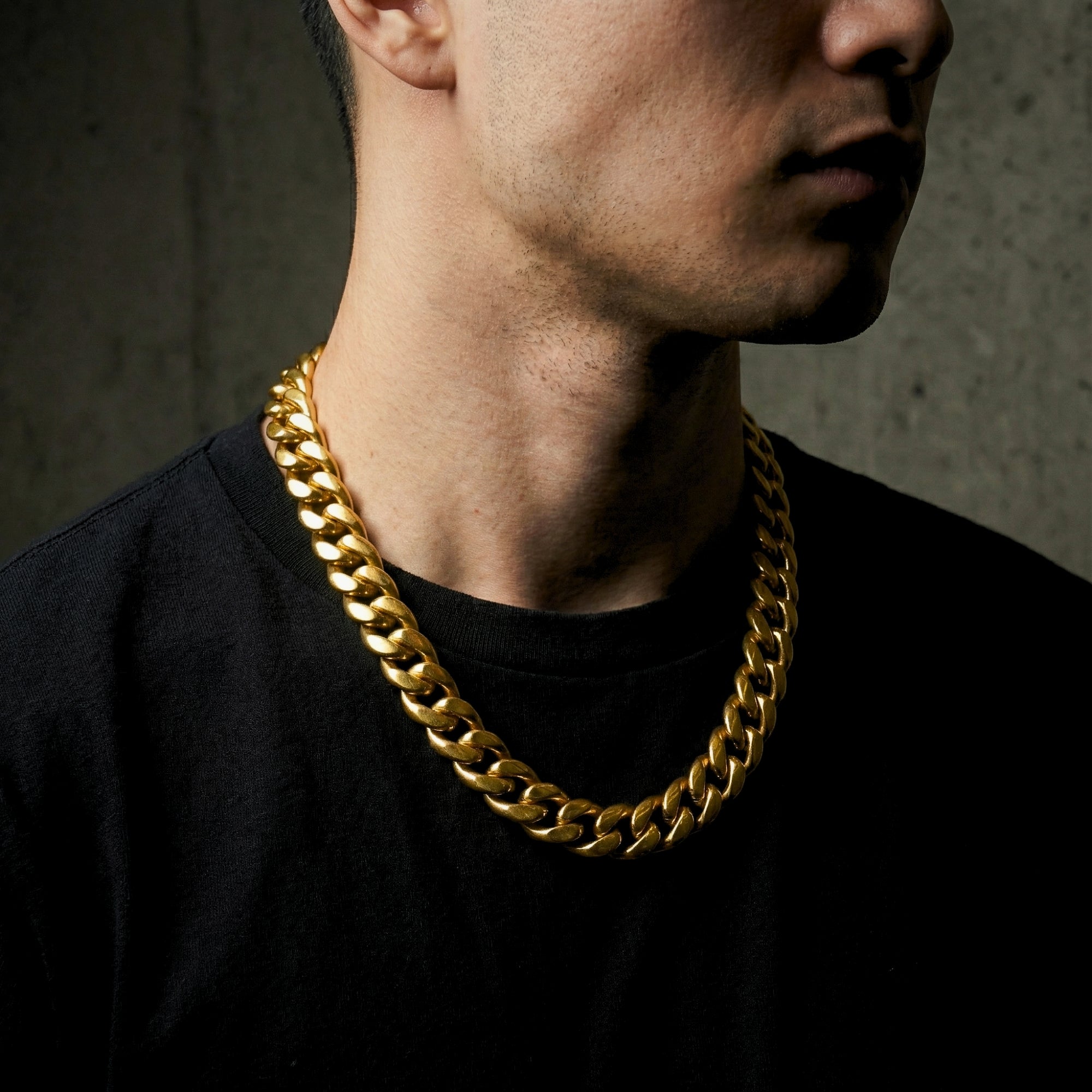 Side view of a model wearing the 12mm gold-tone stainless steel Emperor Cuban link chain.
