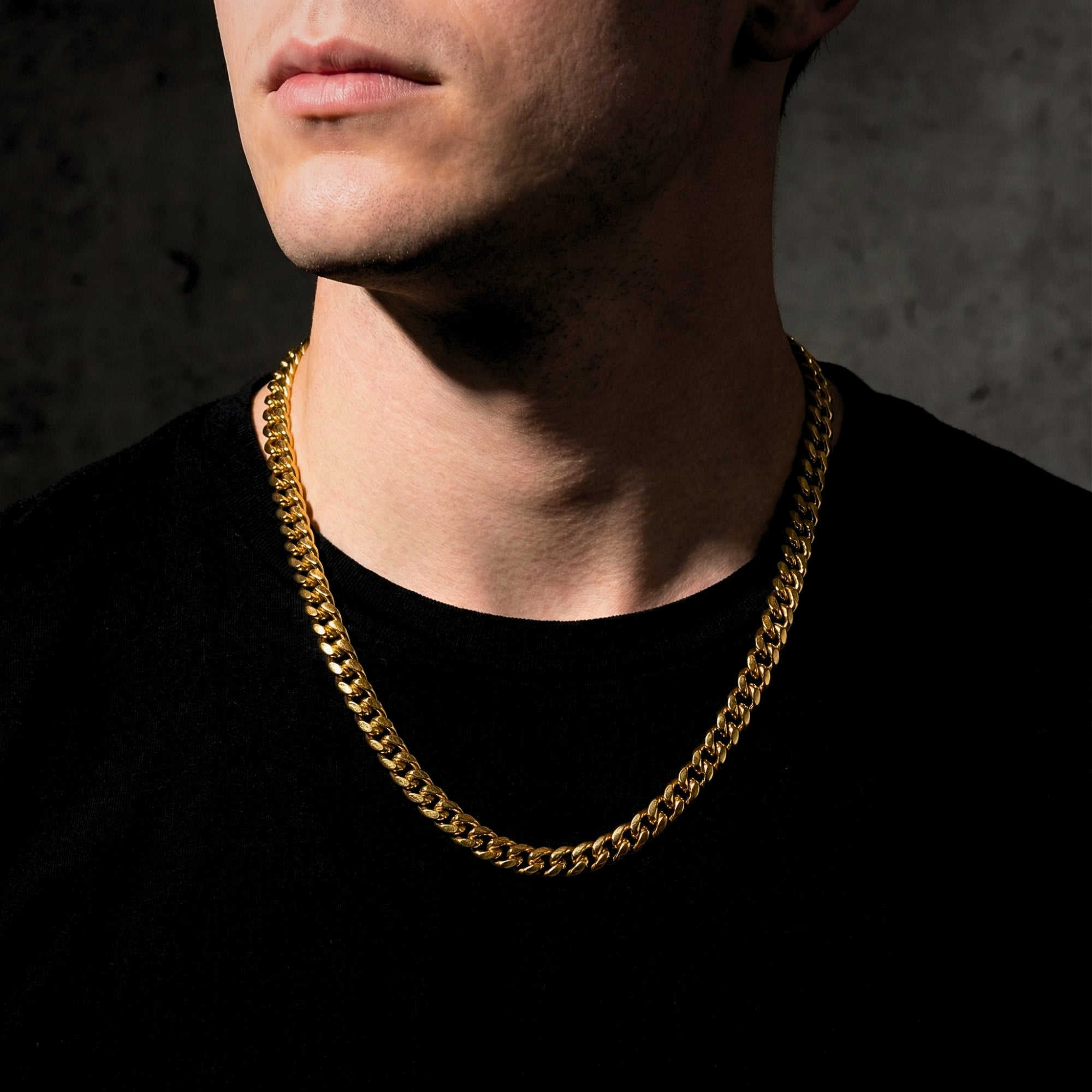Man wearing the 8mm gold stainless steel Cuban link chain necklace against a dark background.