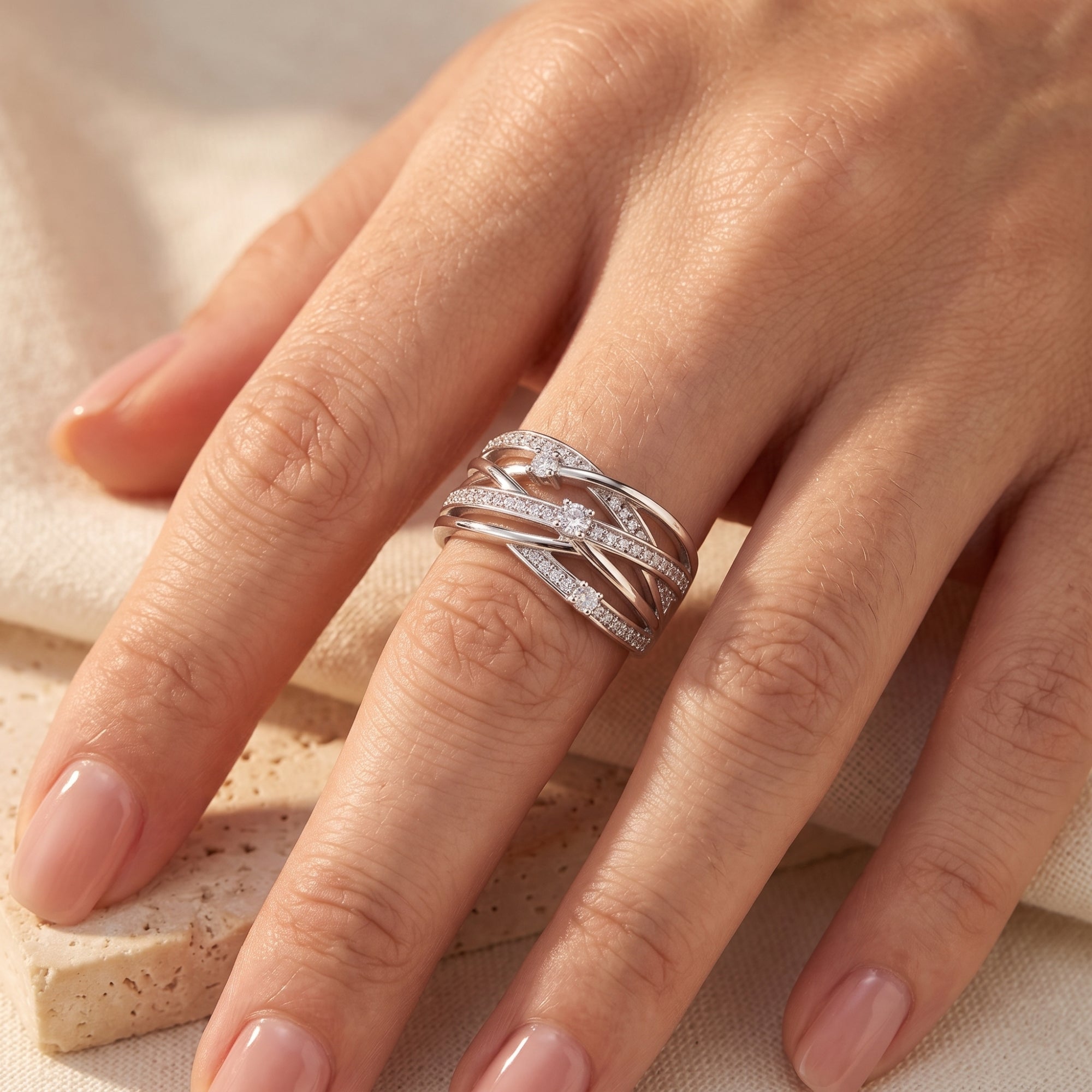 Interwoven silver crossover band with cubic zirconia accents on a model's finger.