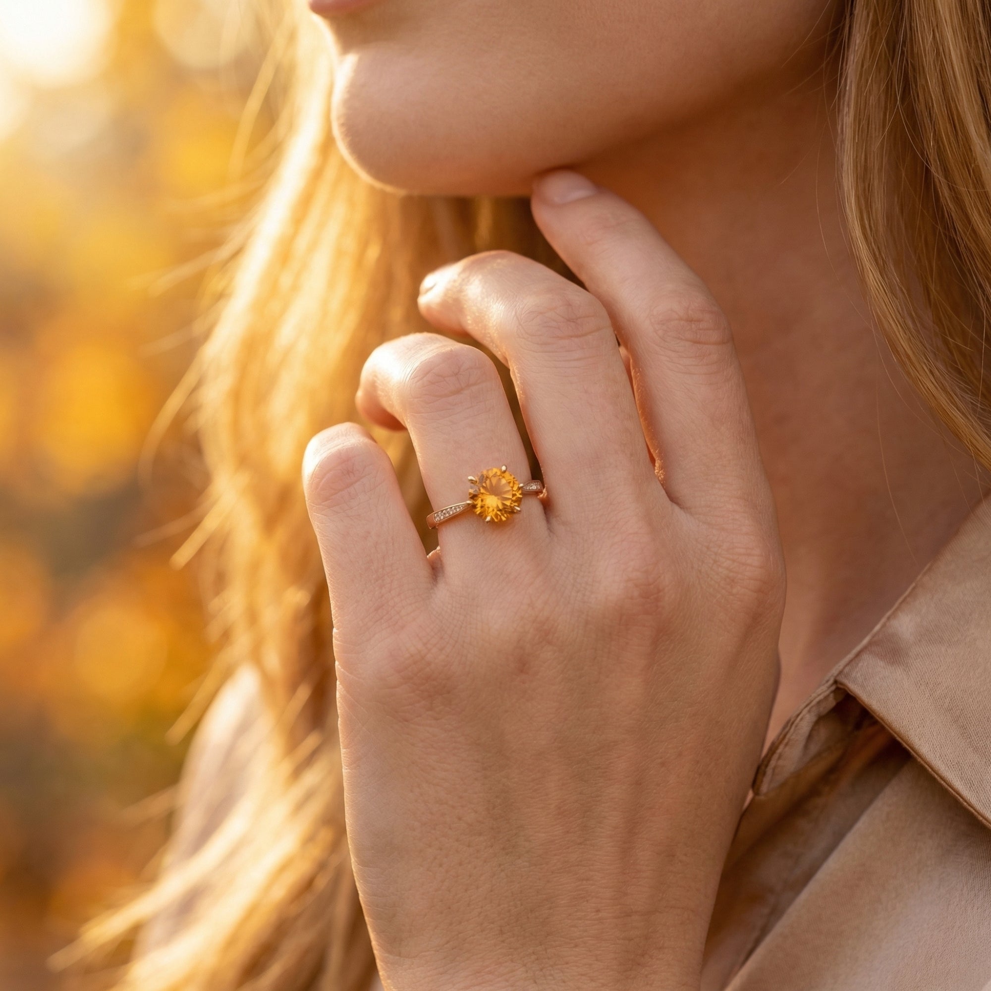 18K yellow gold citrine ring with a round center stone worn on a model's hand in golden hour light.