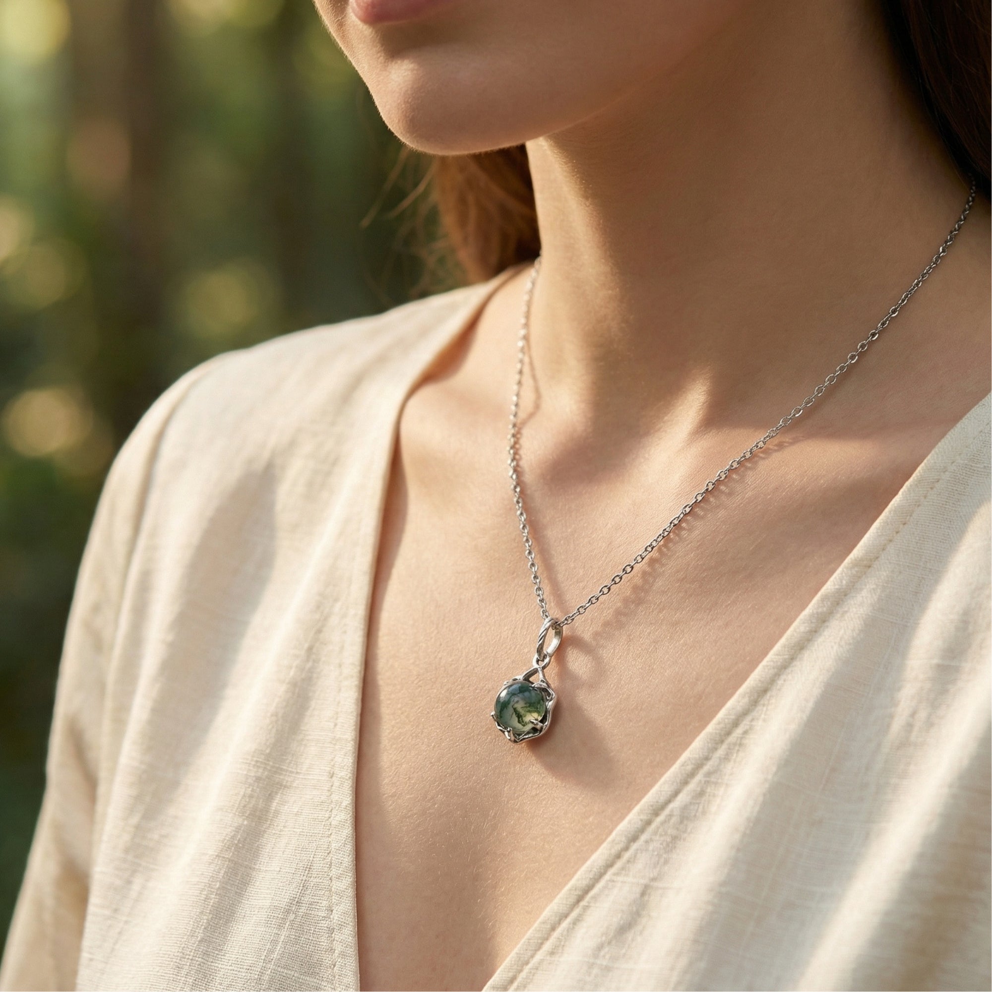 Close-up of a woman wearing the sterling silver celtic knot pendant necklace with a round natural moss agate stone.