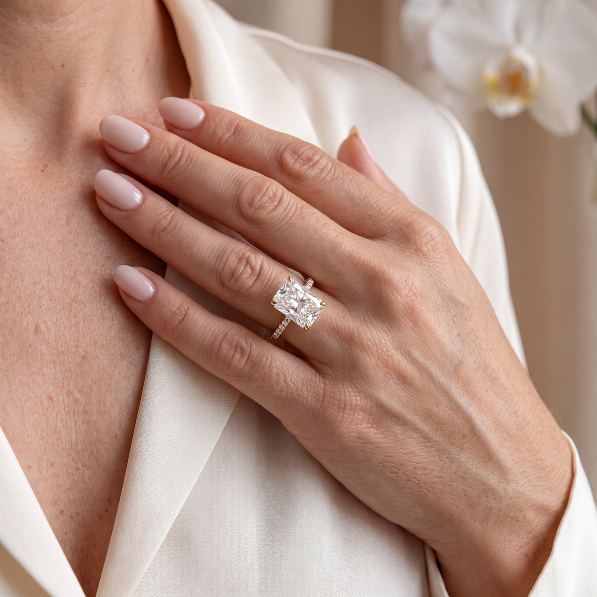 Close-up of a hand wearing a radiant cut moissanite engagement ring in yellow gold.