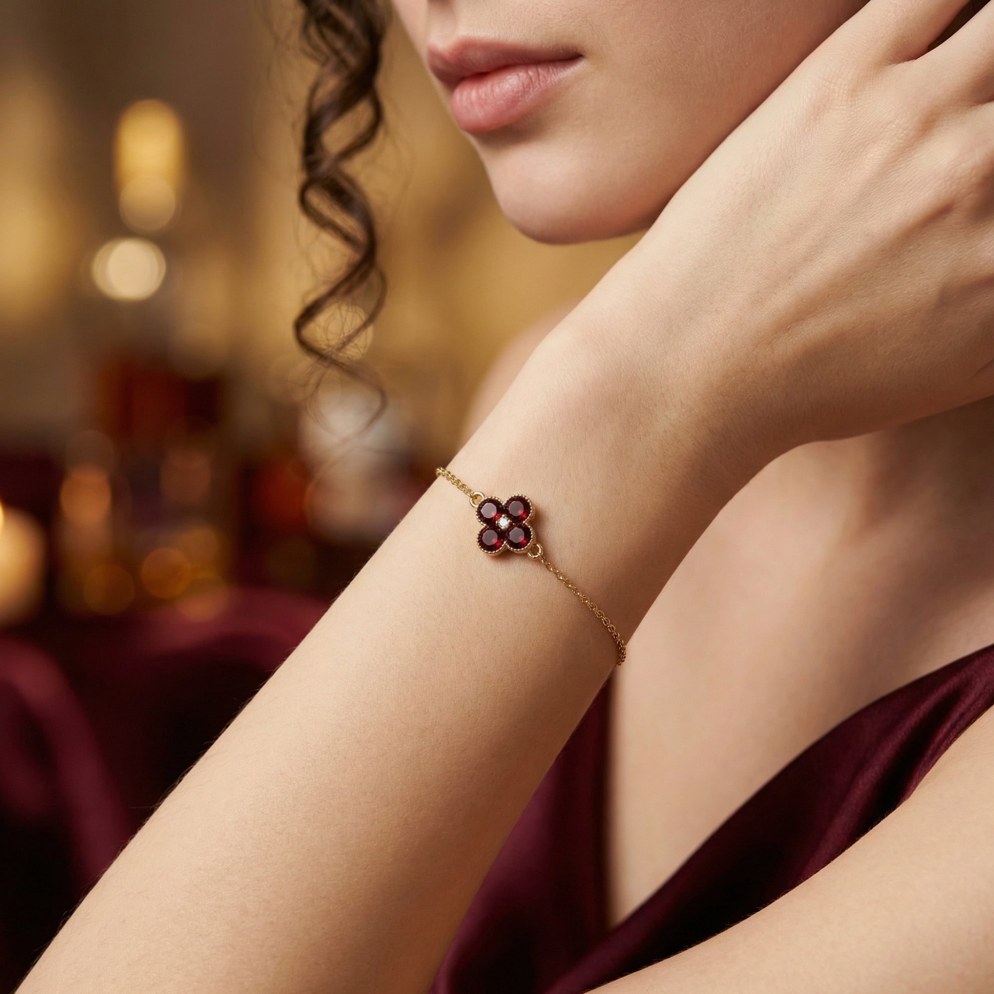 18K yellow gold garnet station bracelet shown on a model's wrist against a warm, blurred background.