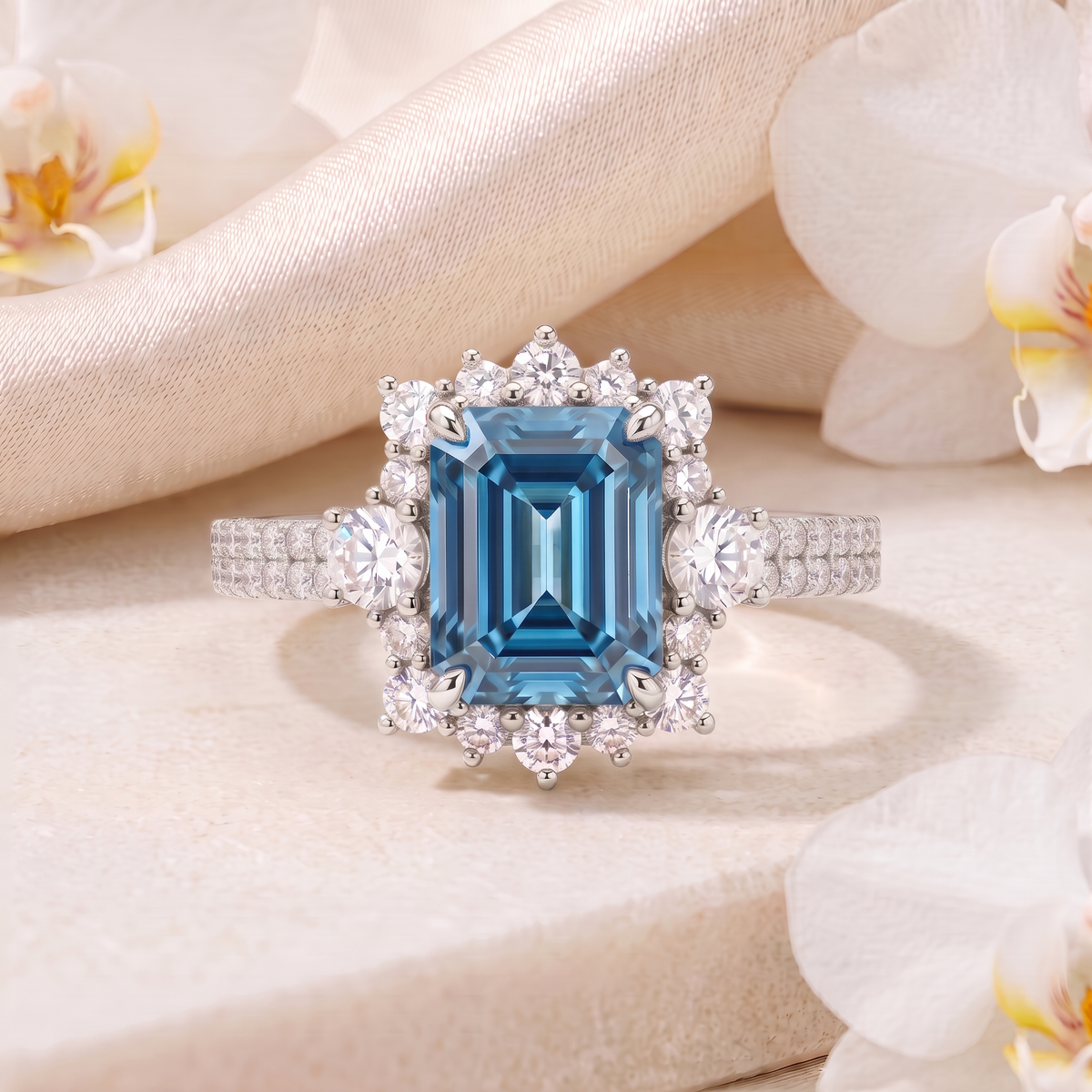 Emerald-cut blue moissanite halo ring with double pavé band in white gold.