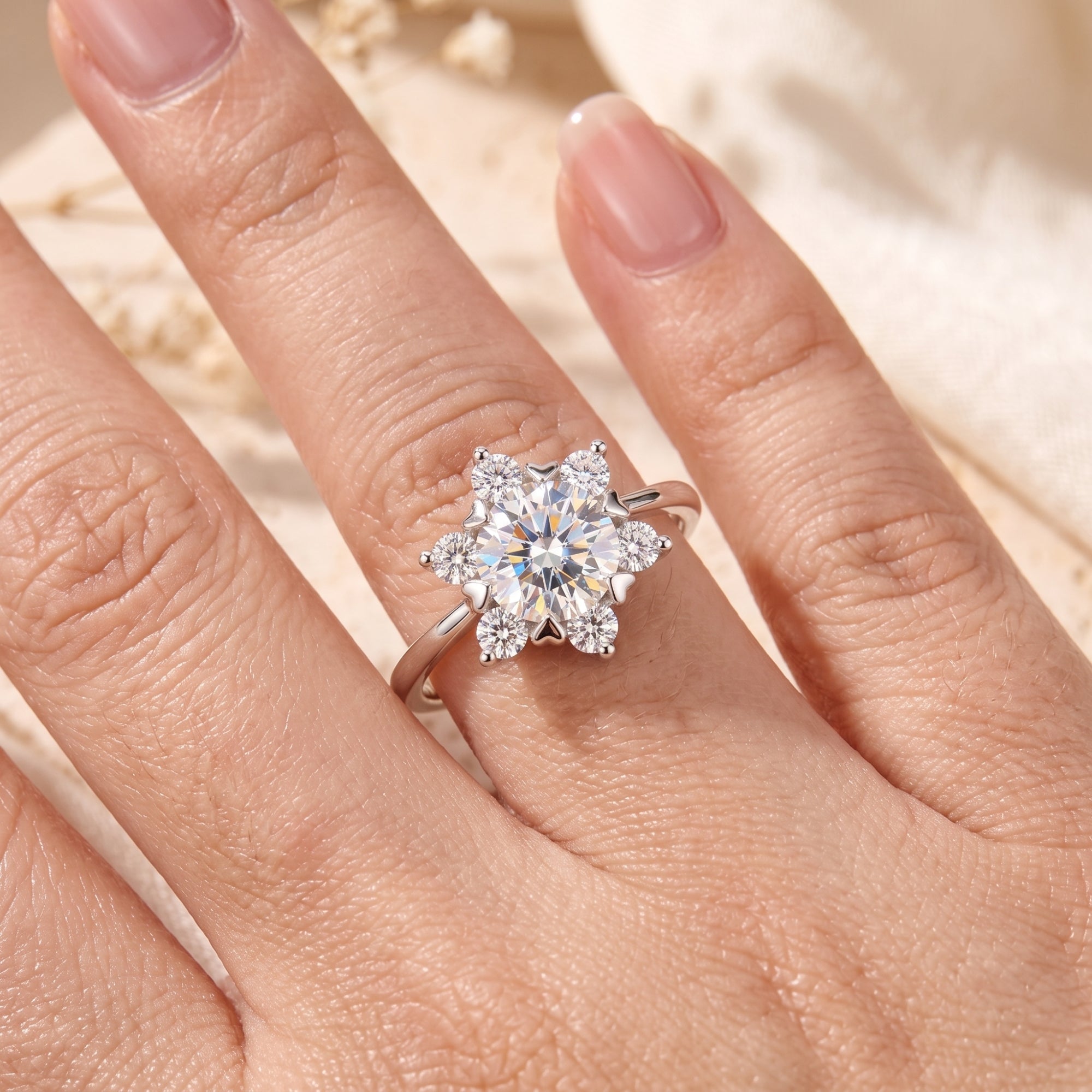 Top-down view of a silver snowflake-style cluster ring with simulated diamonds on a hand.