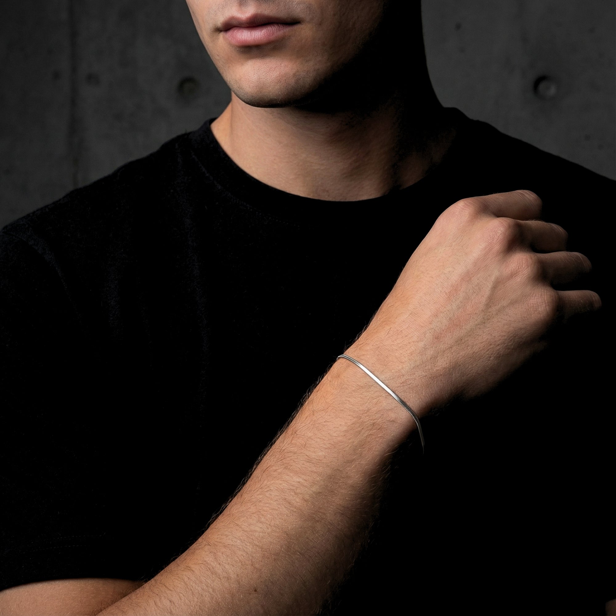 Polished silver square link bracelet for men shown on a model's wrist against a dark background.