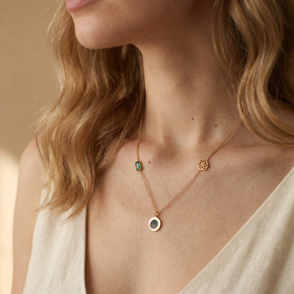 Modelo con collar dorado de estaciones y top blanco con escote en V.