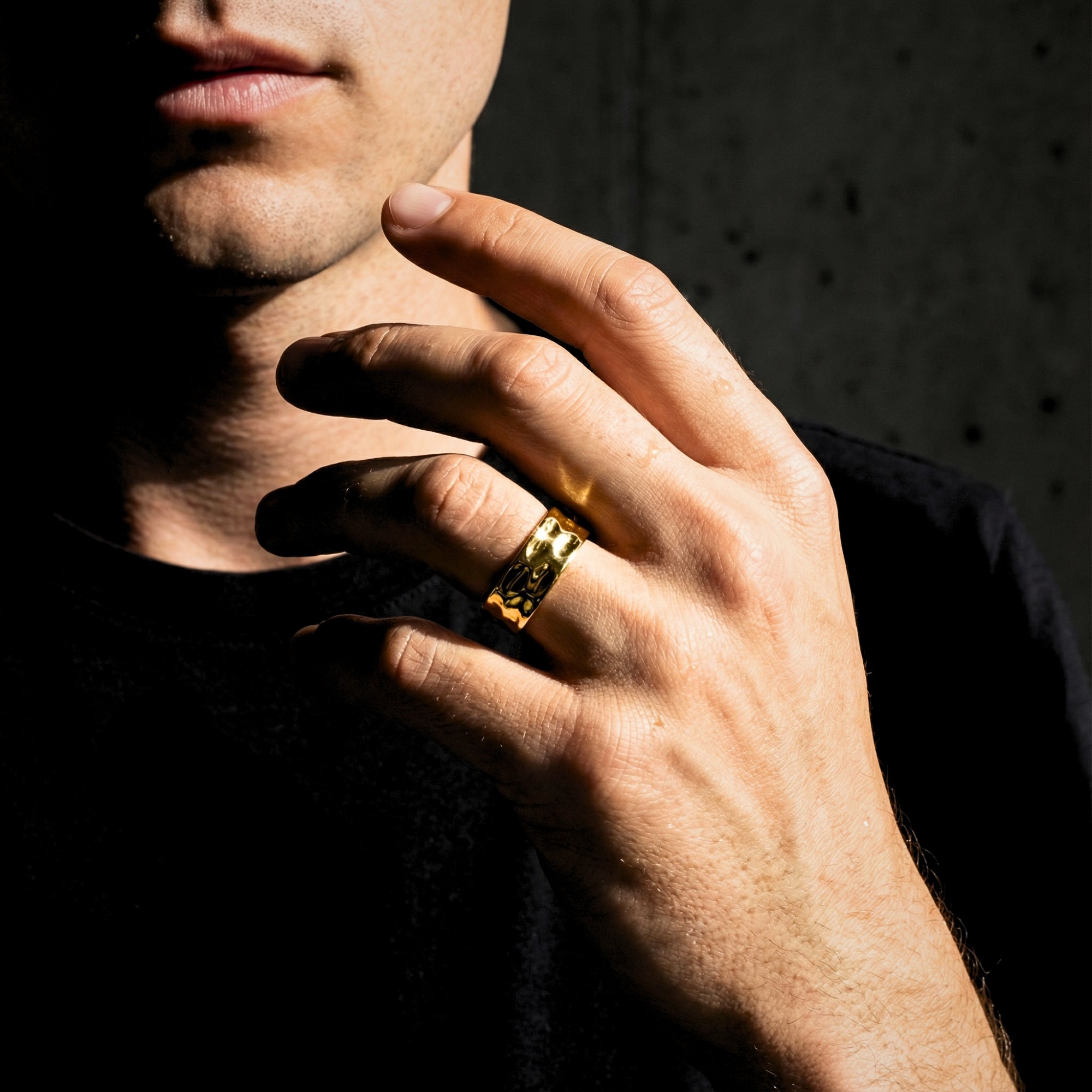 Close-up of a man's hand wearing the gold stainless steel Origin Flow band ring, showcasing its modern minimalist style.