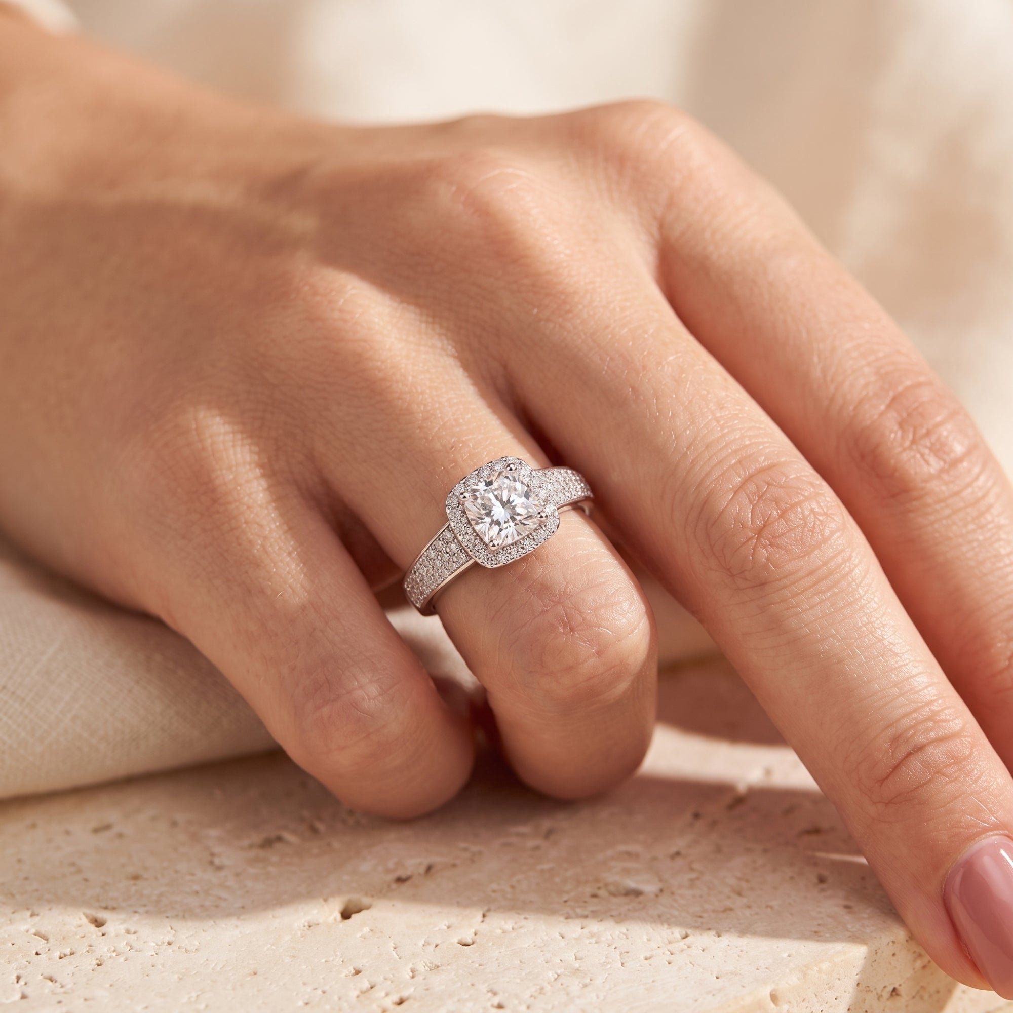 Sterling silver cushion halo promise ring worn on finger.