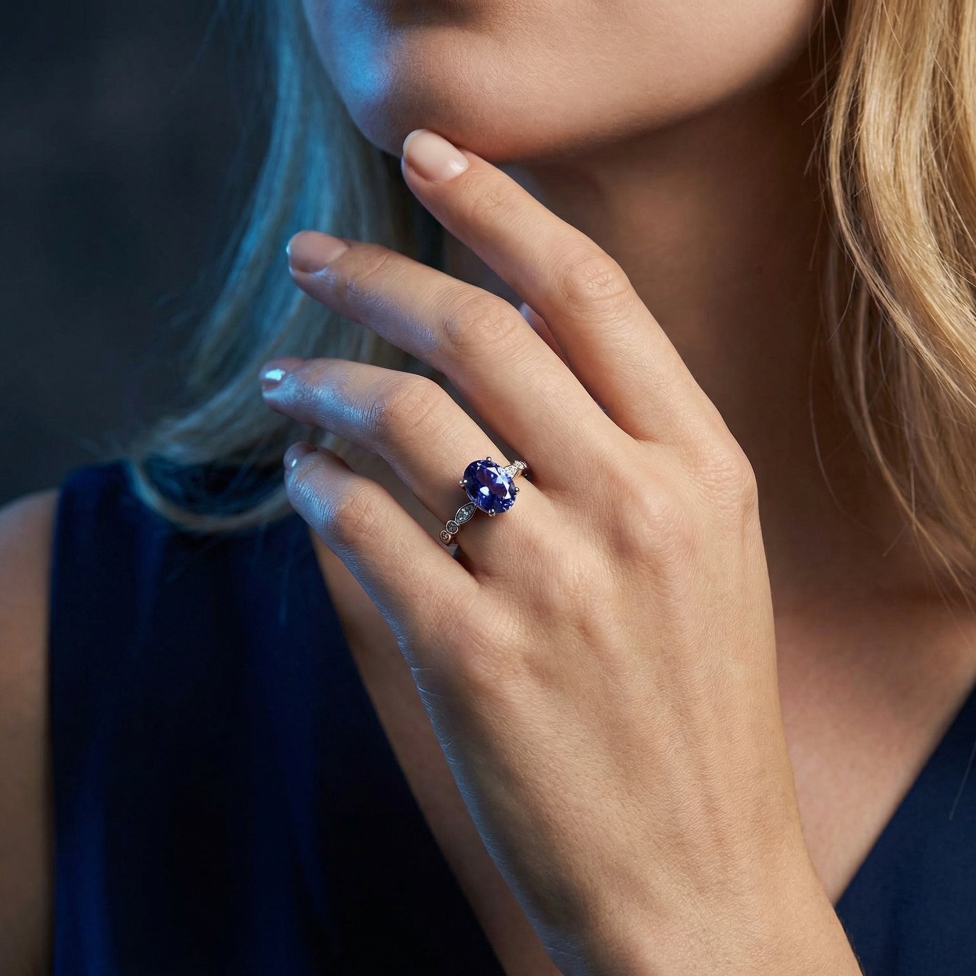 Sterling silver ring featuring a vibrant oval tanzanite center stone worn on a model's hand.