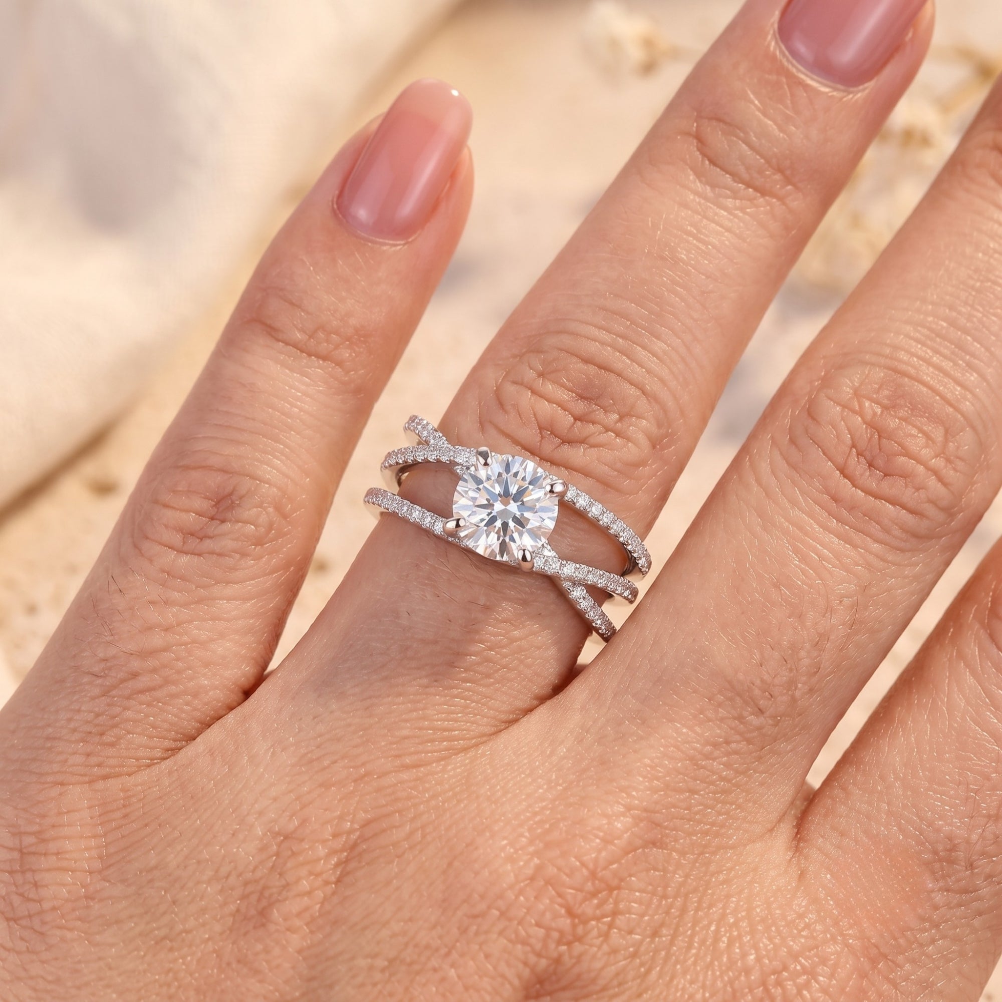 Top view of silver criss-cross promise ring with round stone on a finger for scale.