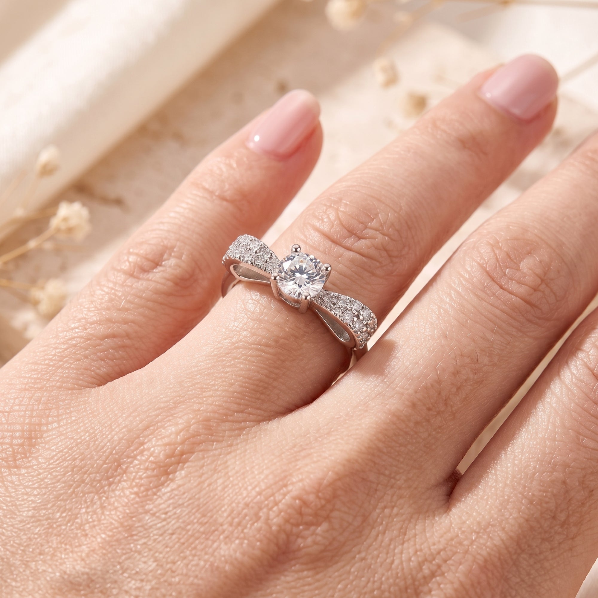Angled view of the sterling silver Juliet bow ring with cubic zirconia on a model's hand.