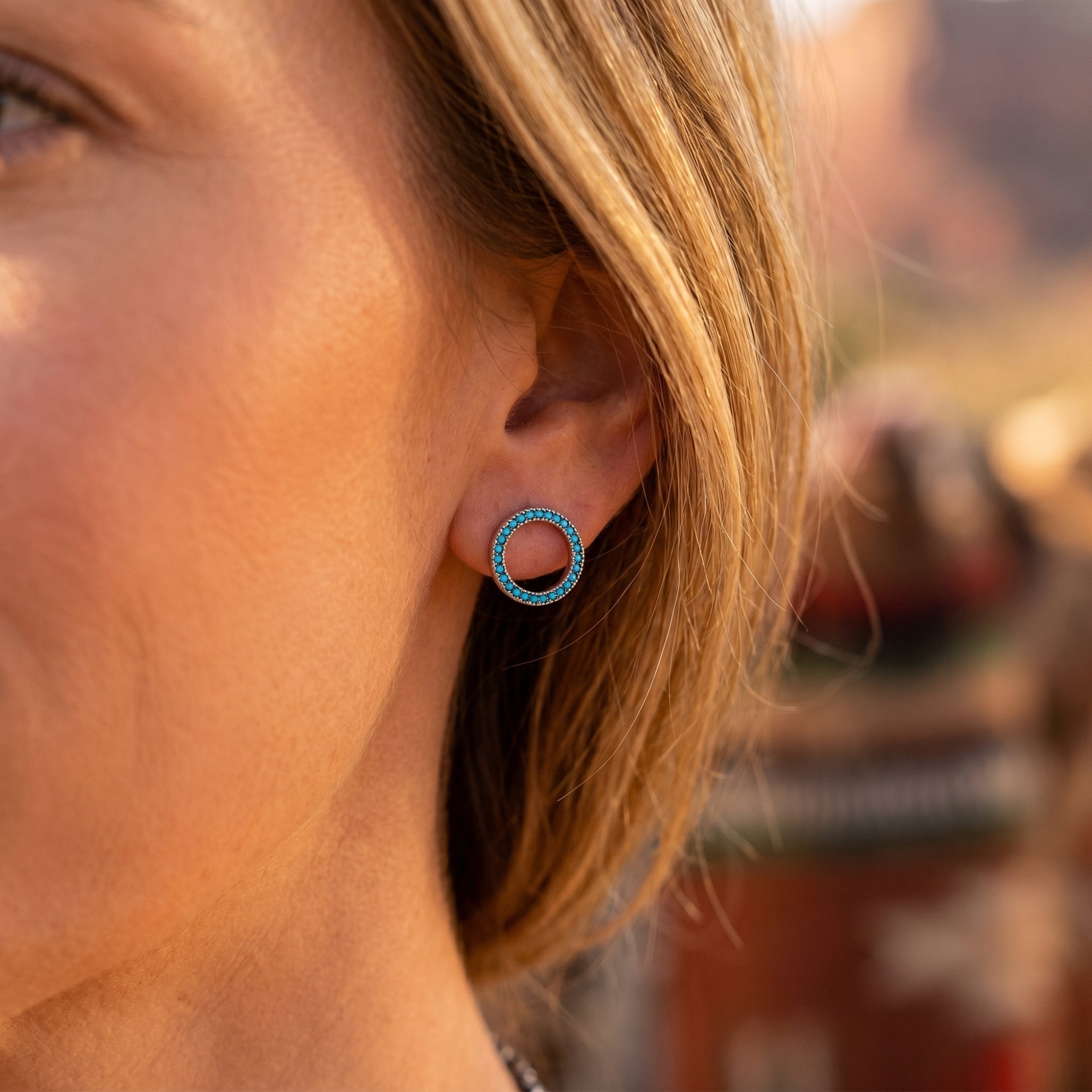 Side view of a model wearing the silver turquoise circle stud earrings in a desert-inspired setting.