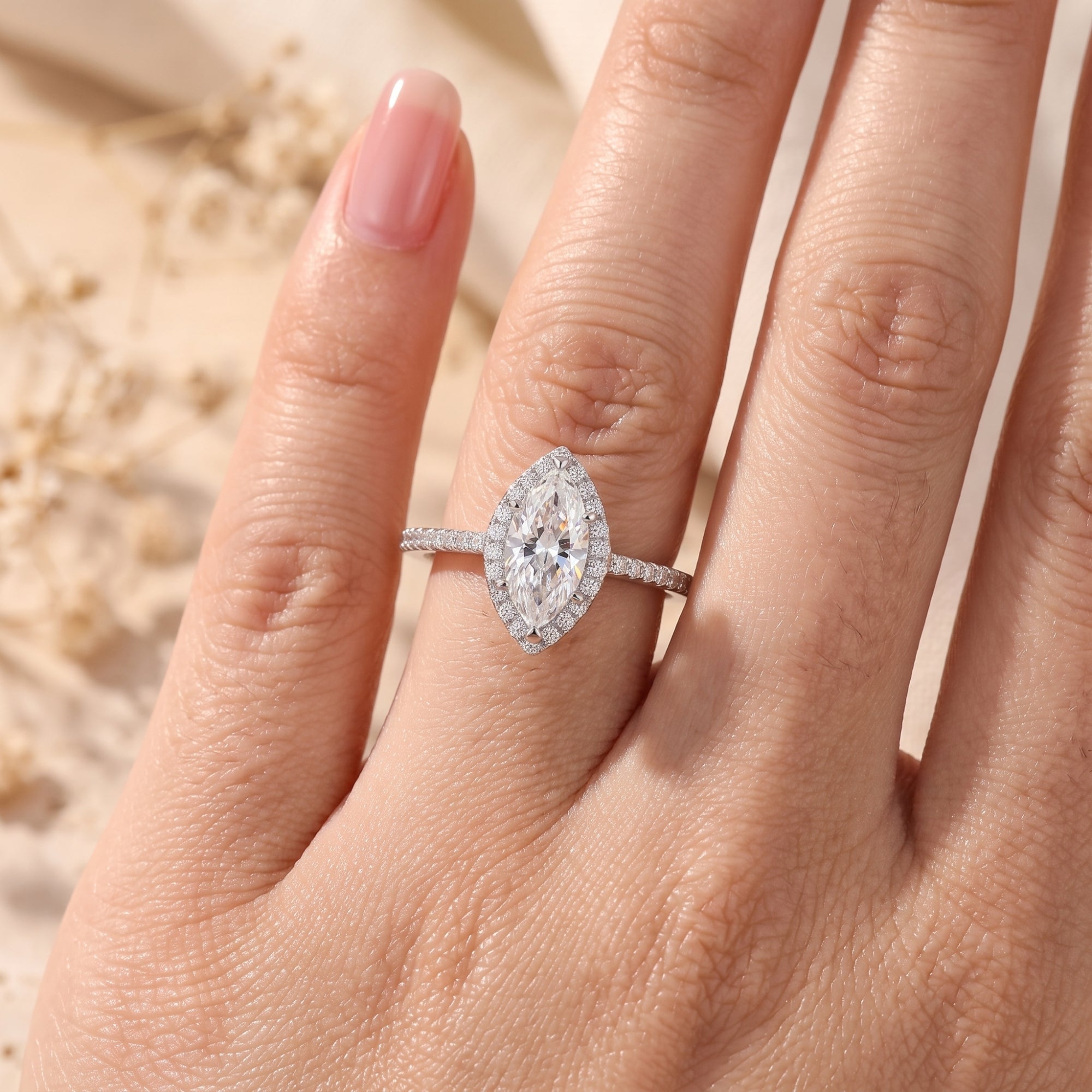Top-down view of the marquise cut simulated diamond halo ring in silver on a model's finger.