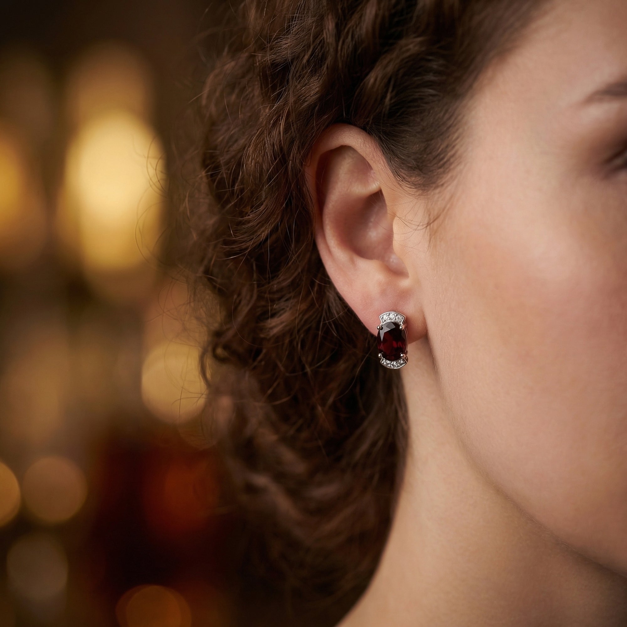 Side view of a model wearing an oval natural garnet and silver drop earring from the January birthstone collection.