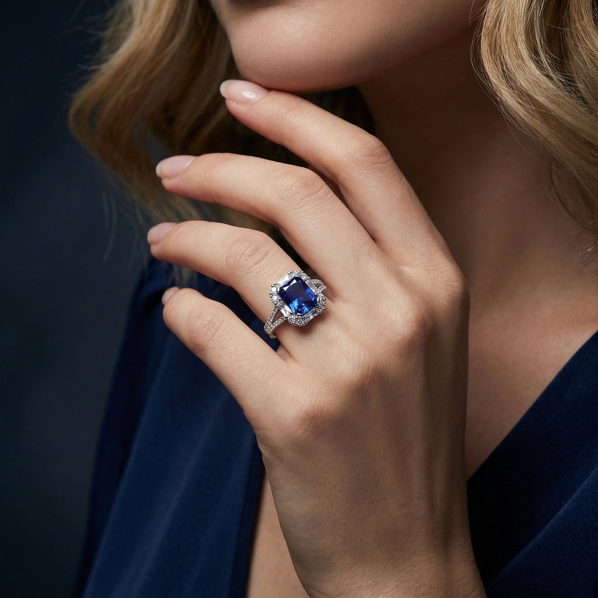 Model wearing the radiant cut tanzanite sterling silver ring on her finger, hand resting near her chin.