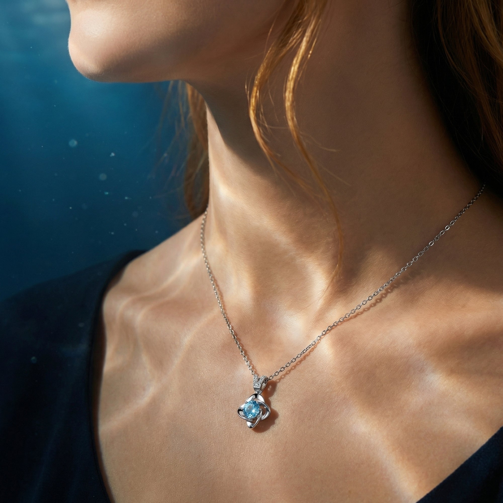 A woman wearing the round cut aquamarine pendant in platinum, showcasing the 16-18 inch adjustable chain length.