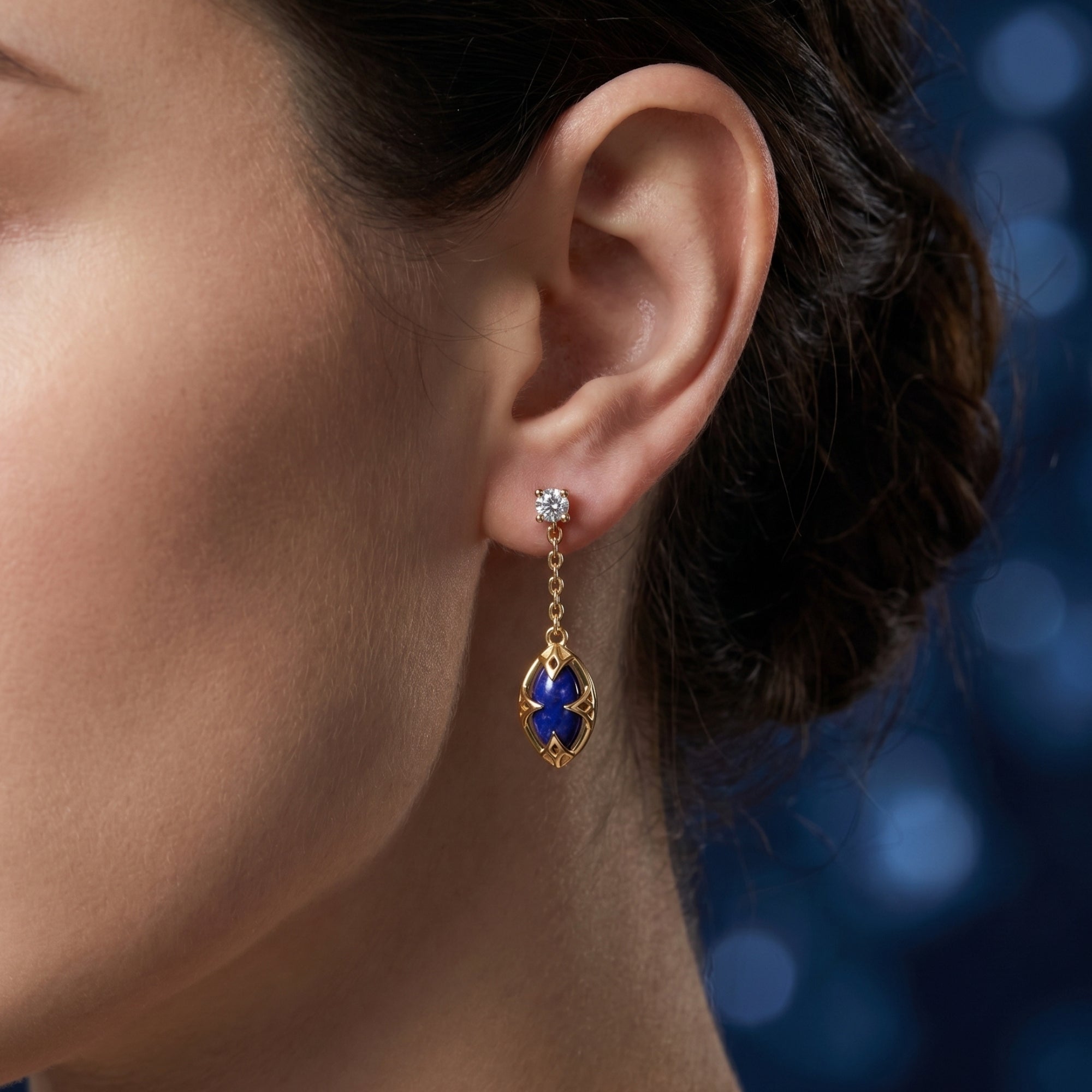 Close-up of an 18k gold plated marquise lapis lazuli drop earring on a model, highlighting the intricate gold cage.