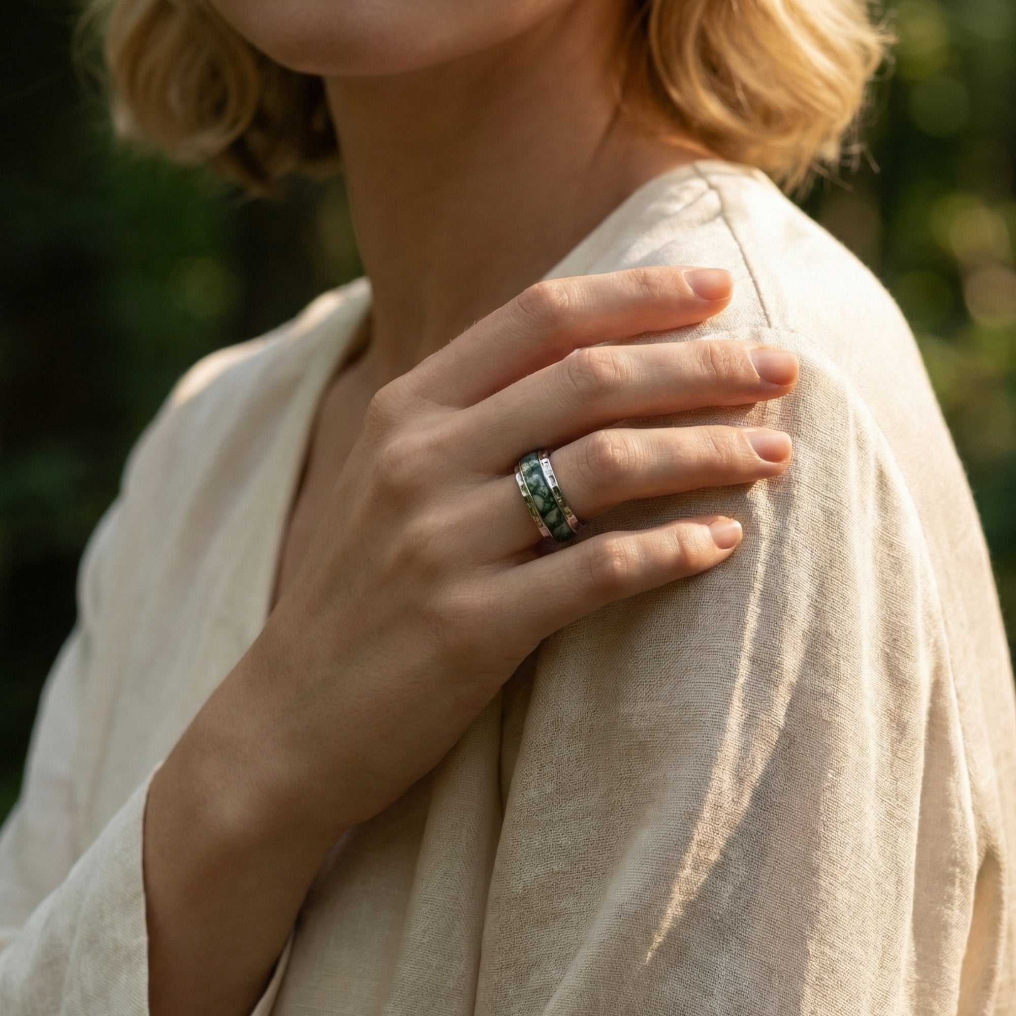 Natural moss agate inlay ring in sterling silver worn on a woman's hand, resting on her shoulder.