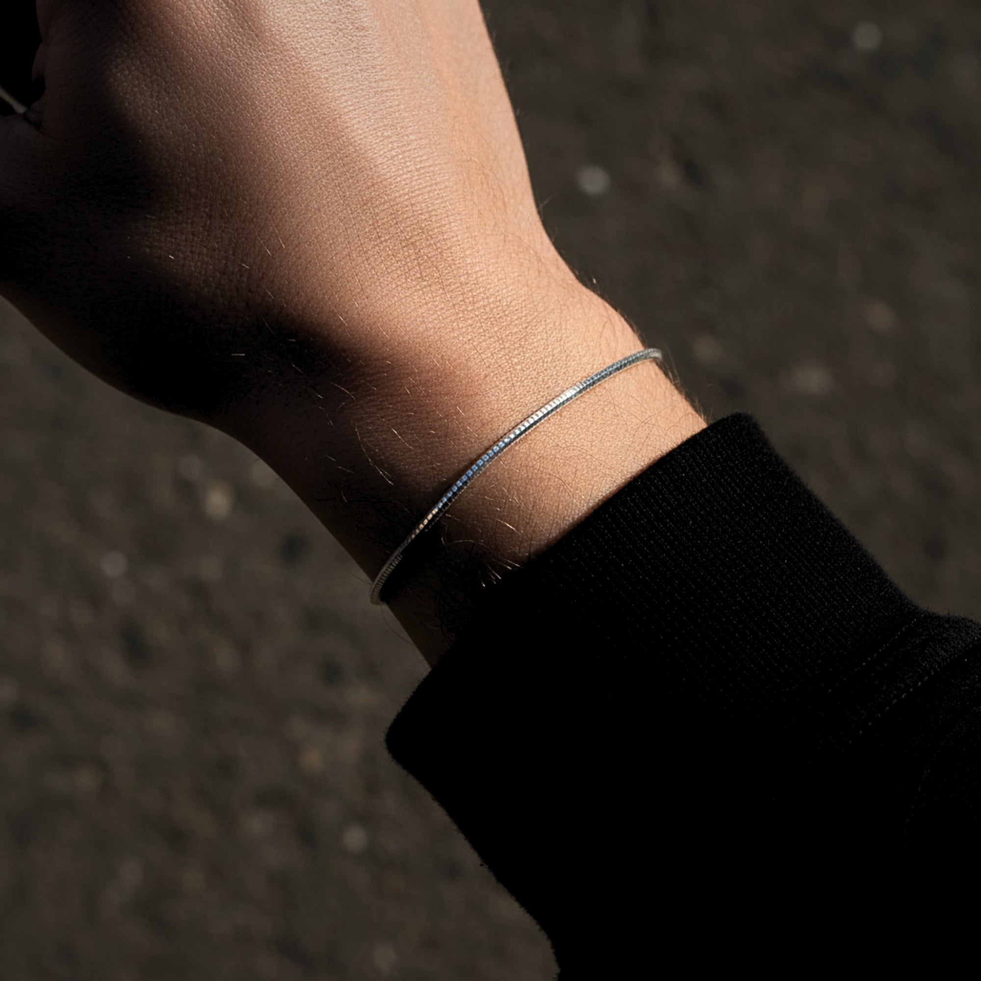 Close-up of a silver stainless steel octagon link bracelet on a man's wrist.