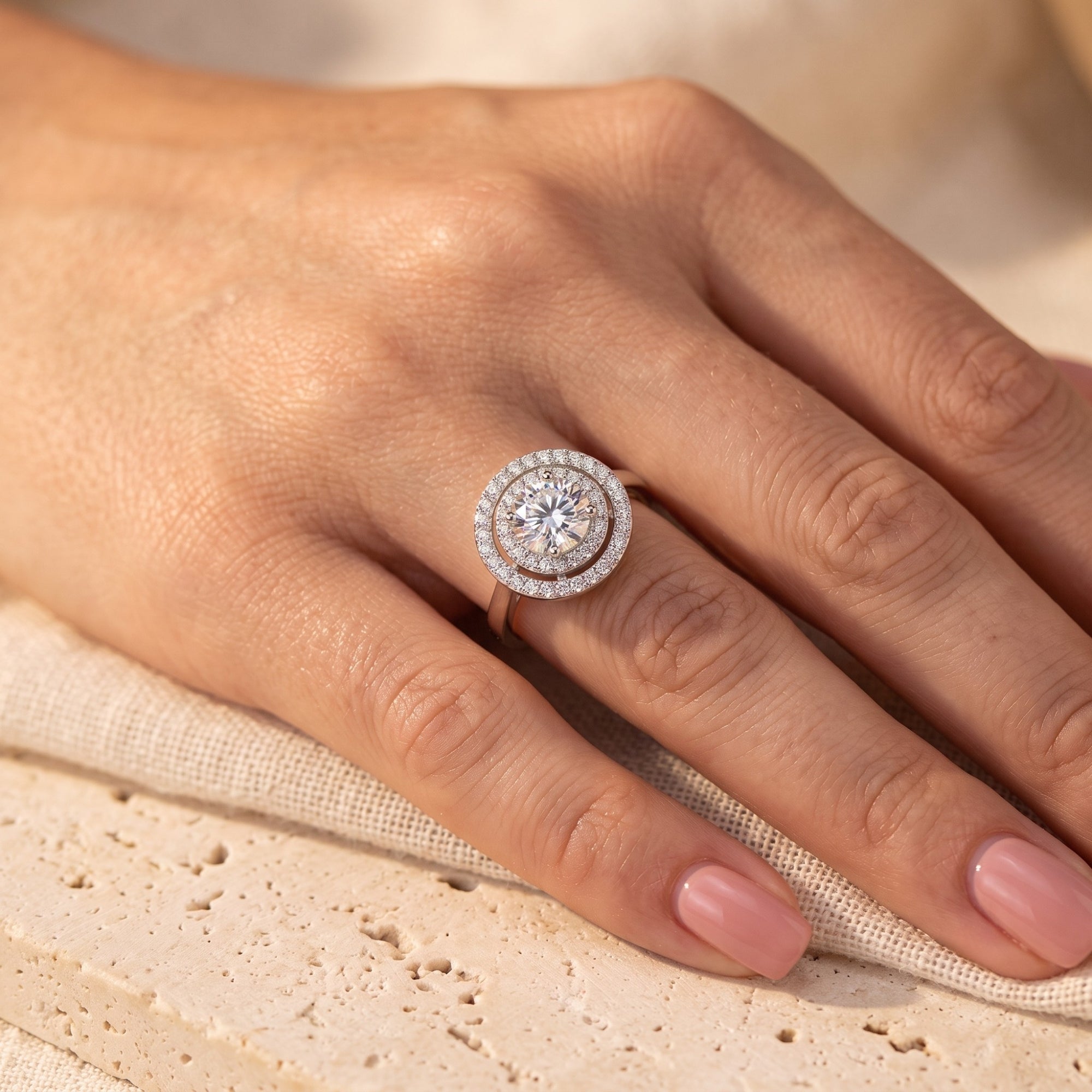 Hand wearing a round cut simulated diamond double halo ring in polished S925 sterling silver.