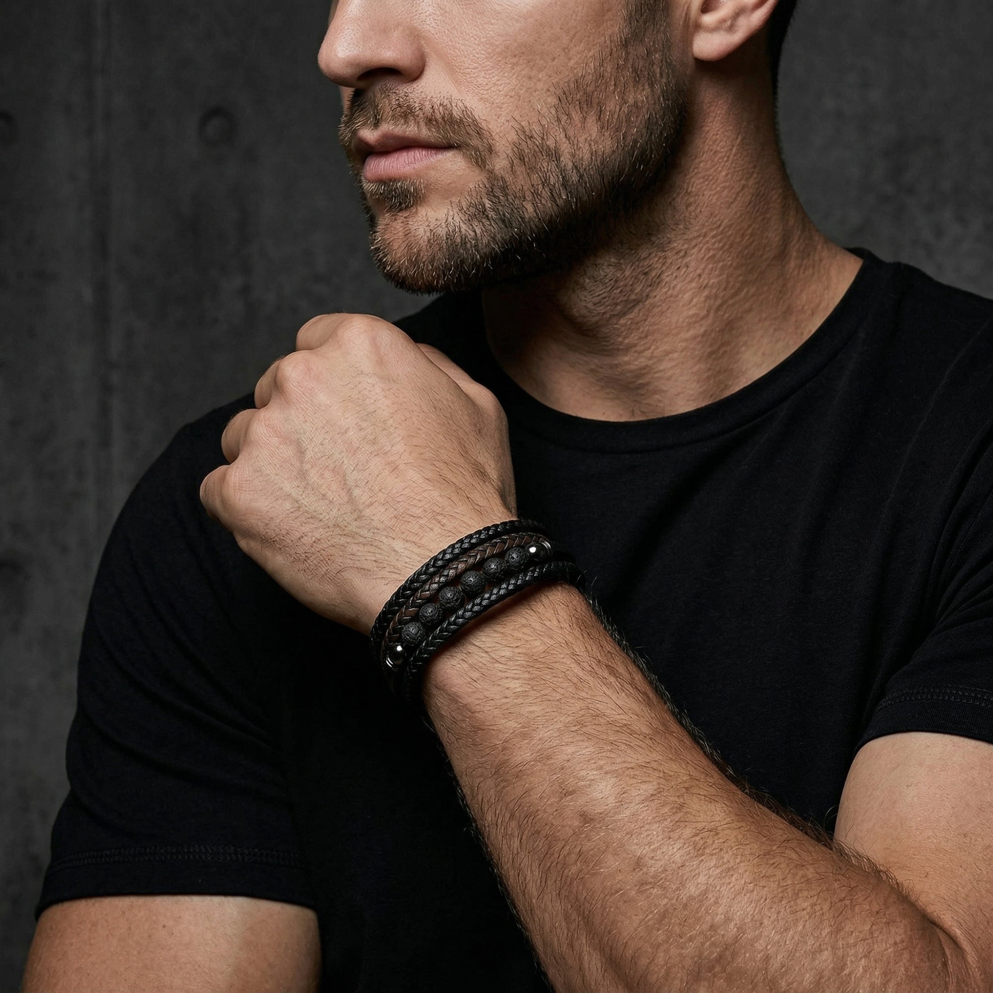 Men's Outrider bracelet in black braided leather and lava stone worn by a model in a black t-shirt.