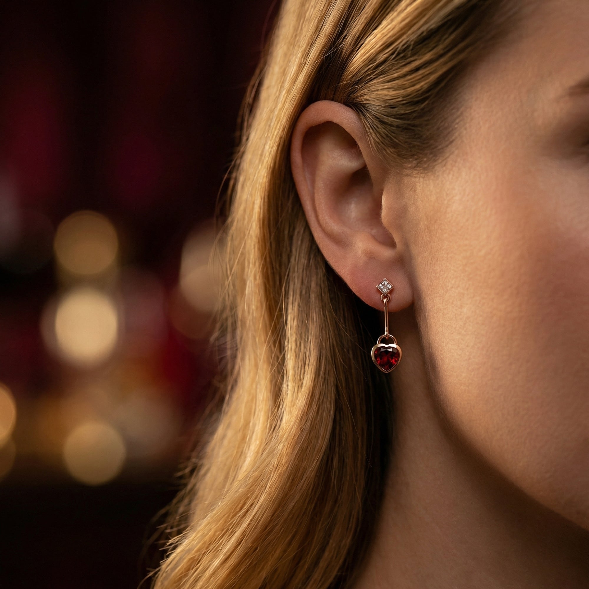 Side profile of a model wearing the Rosalette 18K rose gold and heart-cut red garnet drop earrings.