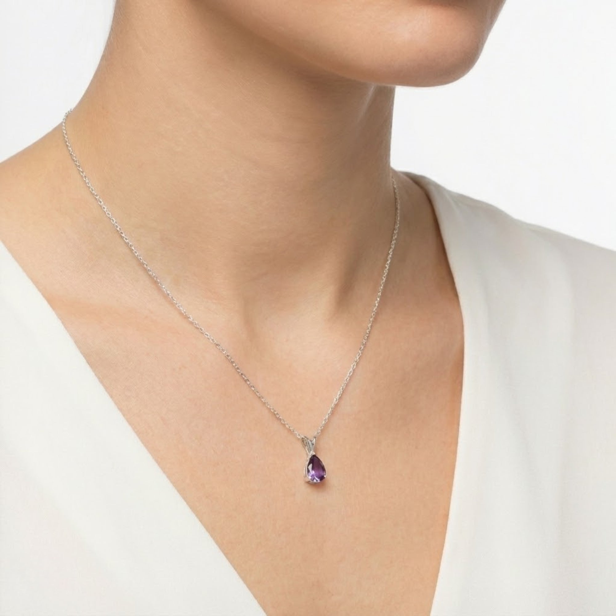 Angled view of a model wearing a teardrop purple moissanite pendant on a silver chain.