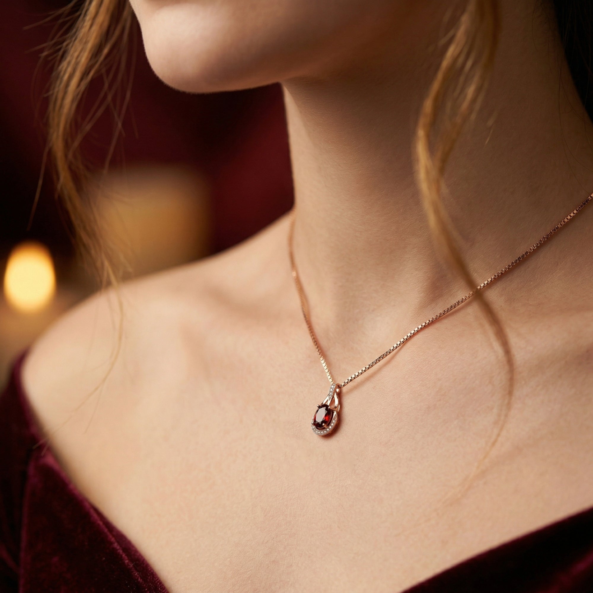 Side view of a model wearing an 18K rose gold pendant necklace with an oval garnet.