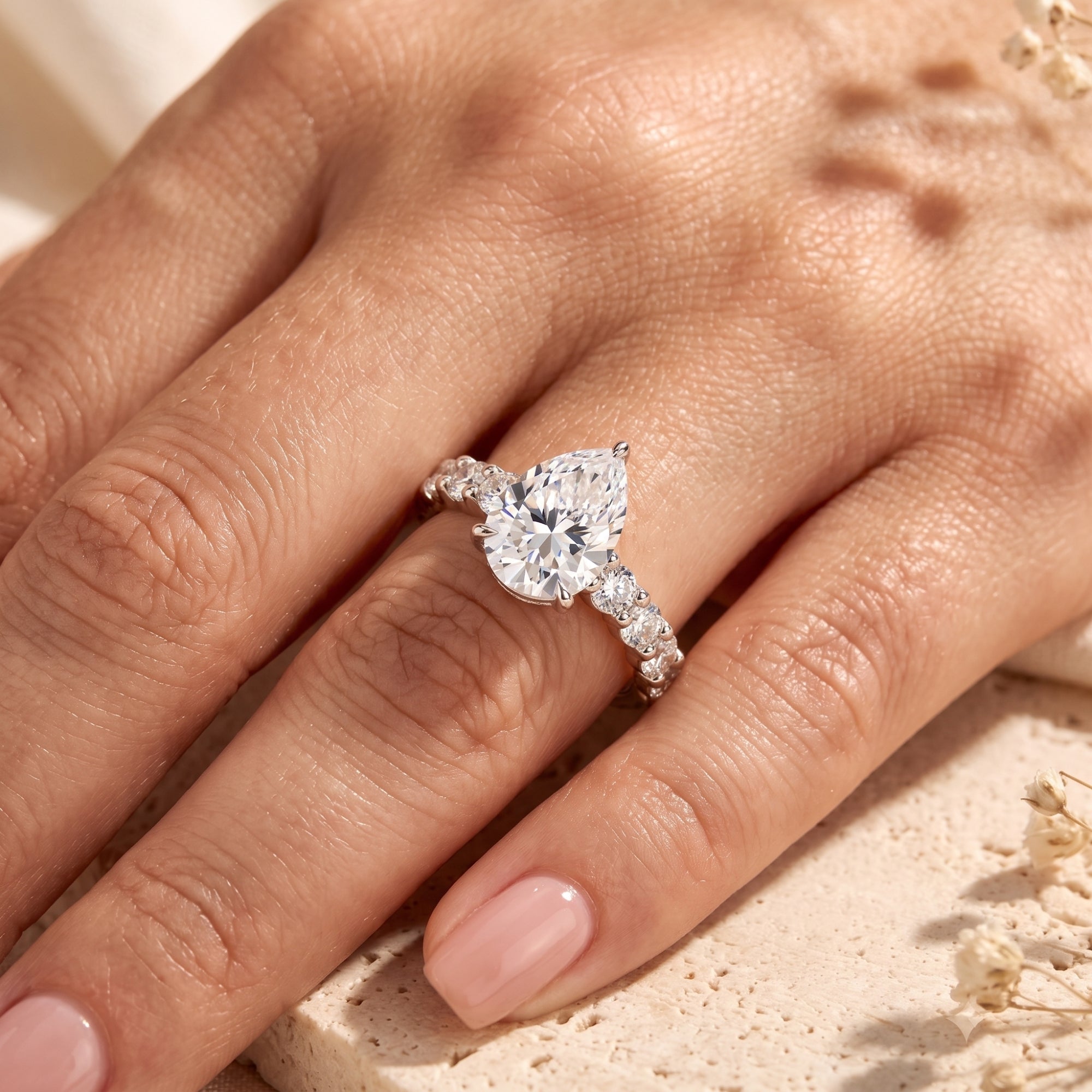 Close-up of a pear-cut silver ring on a hand highlighting the center stone.