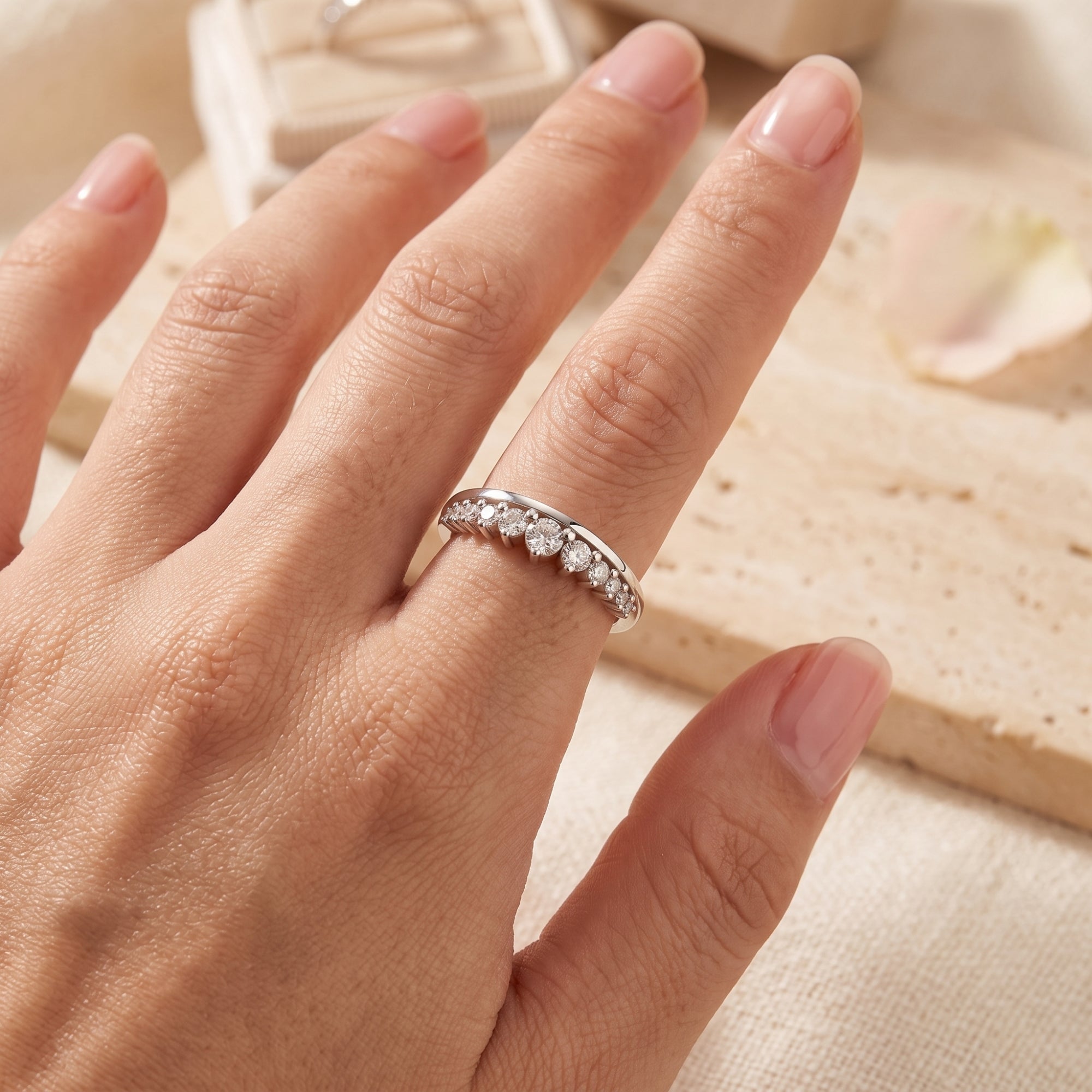 Graduated curved silver ring with simulated diamonds on a hand for scale.