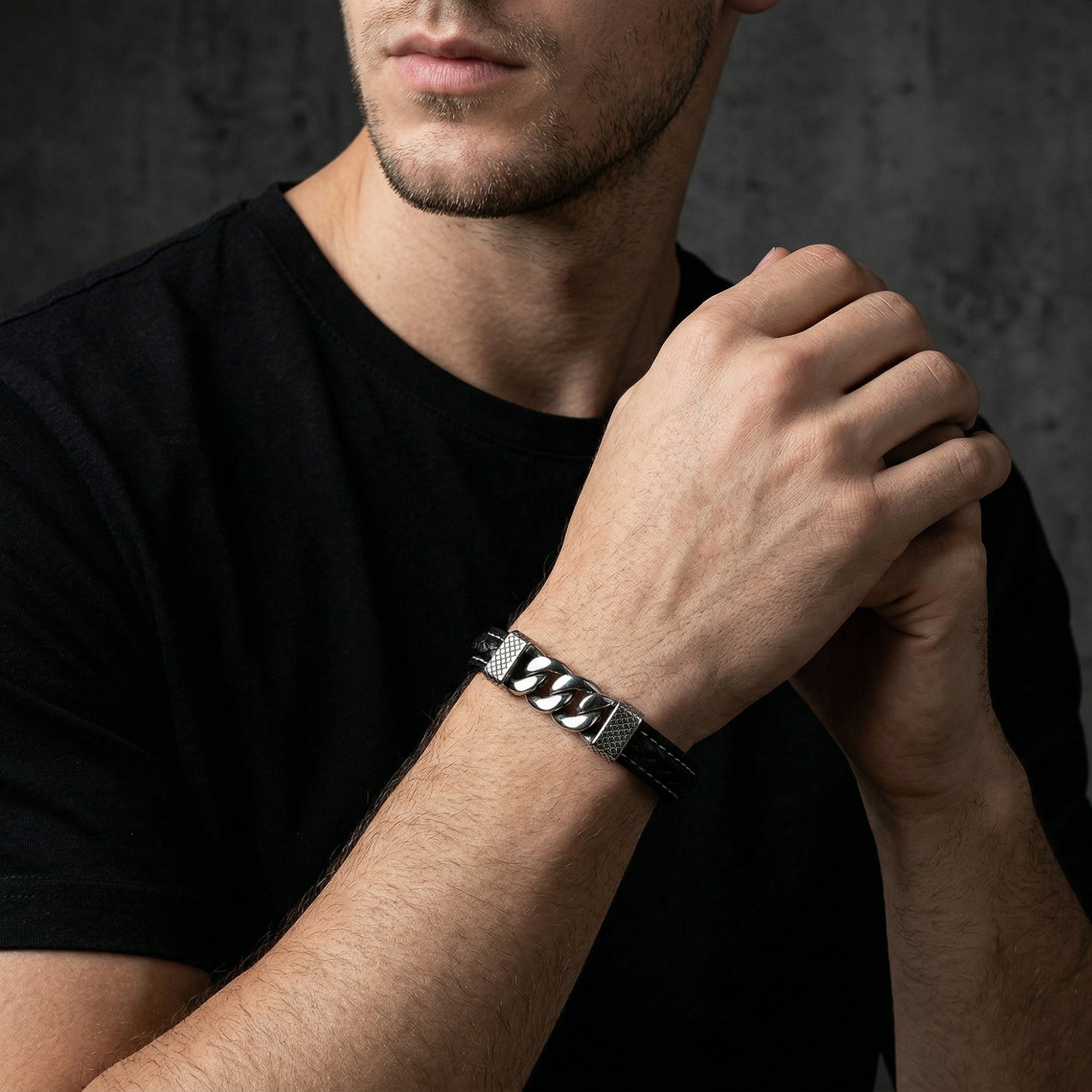 Men's black braided leather bracelet with silver steel links shown on a model's wrist against a dark background.