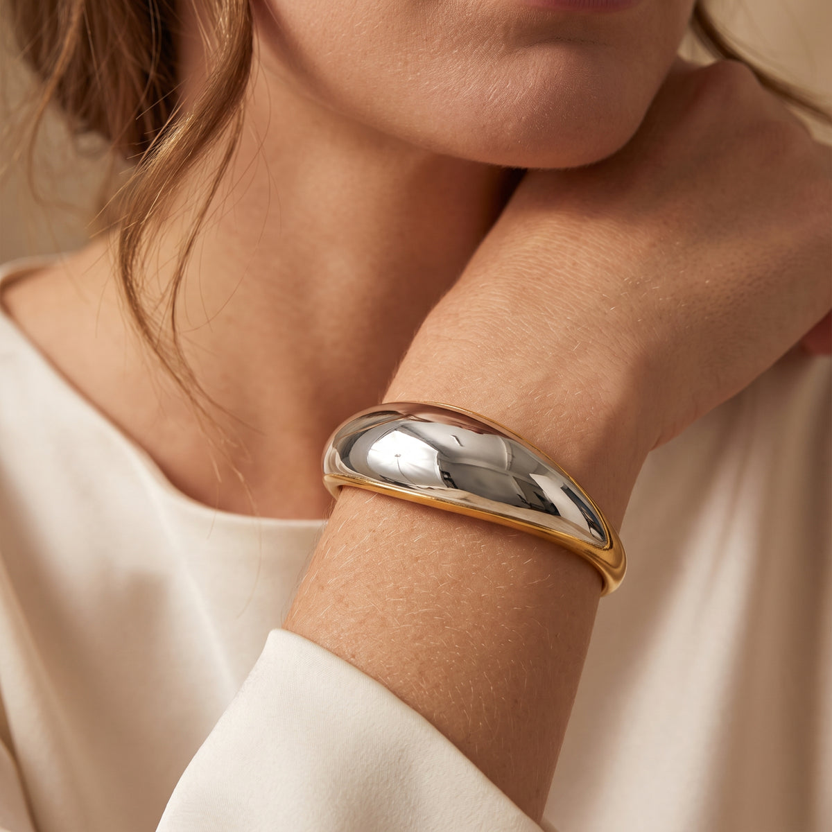 Close-up of the two-tone dome cuff bracelet worn on a model’s wrist, featuring a silver dome with gold edges.