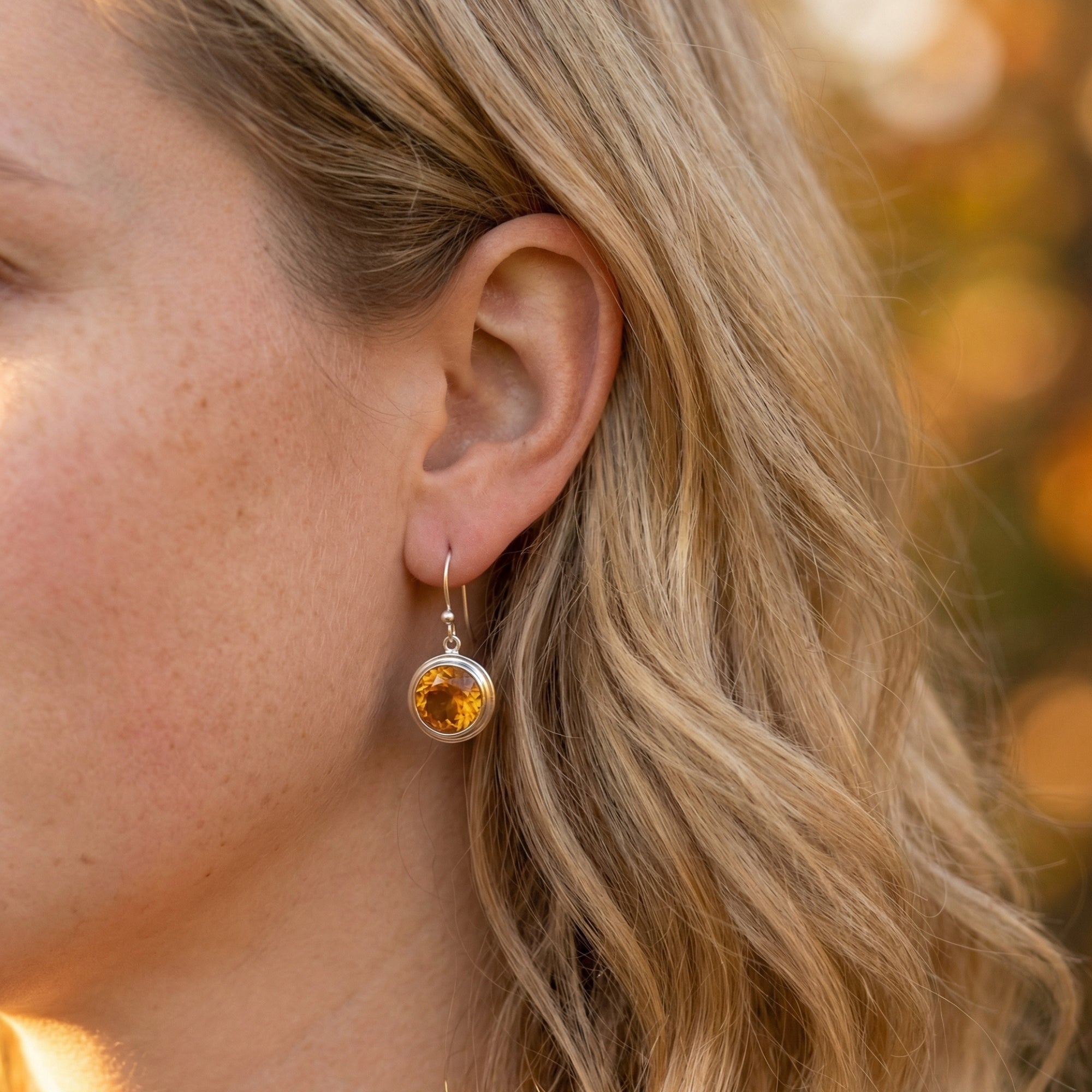 Side view of a model wearing a sterling silver drop earring featuring a round-cut natural citrine.