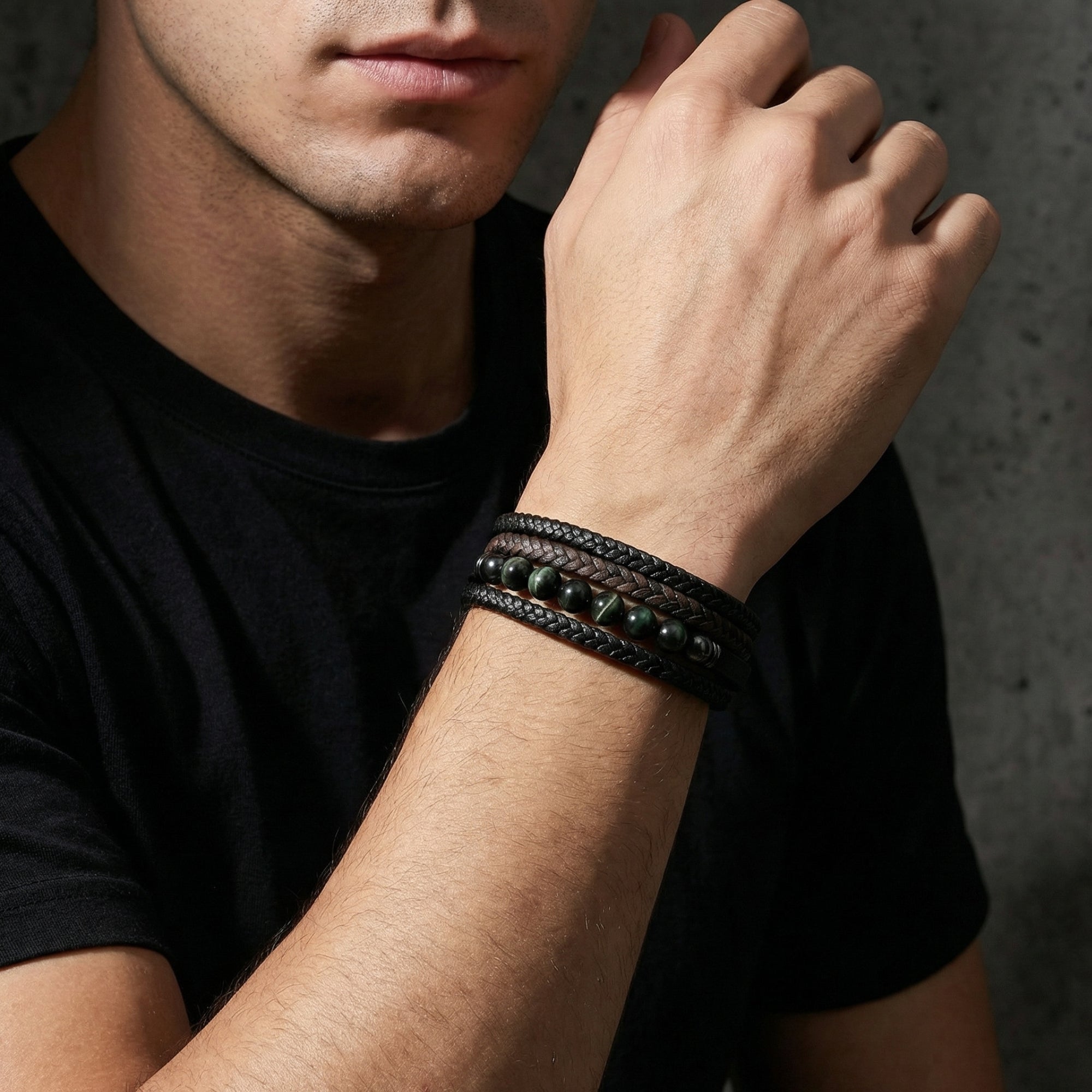 Men's black and brown braided leather bracelet with round stones styled on a model's wrist.