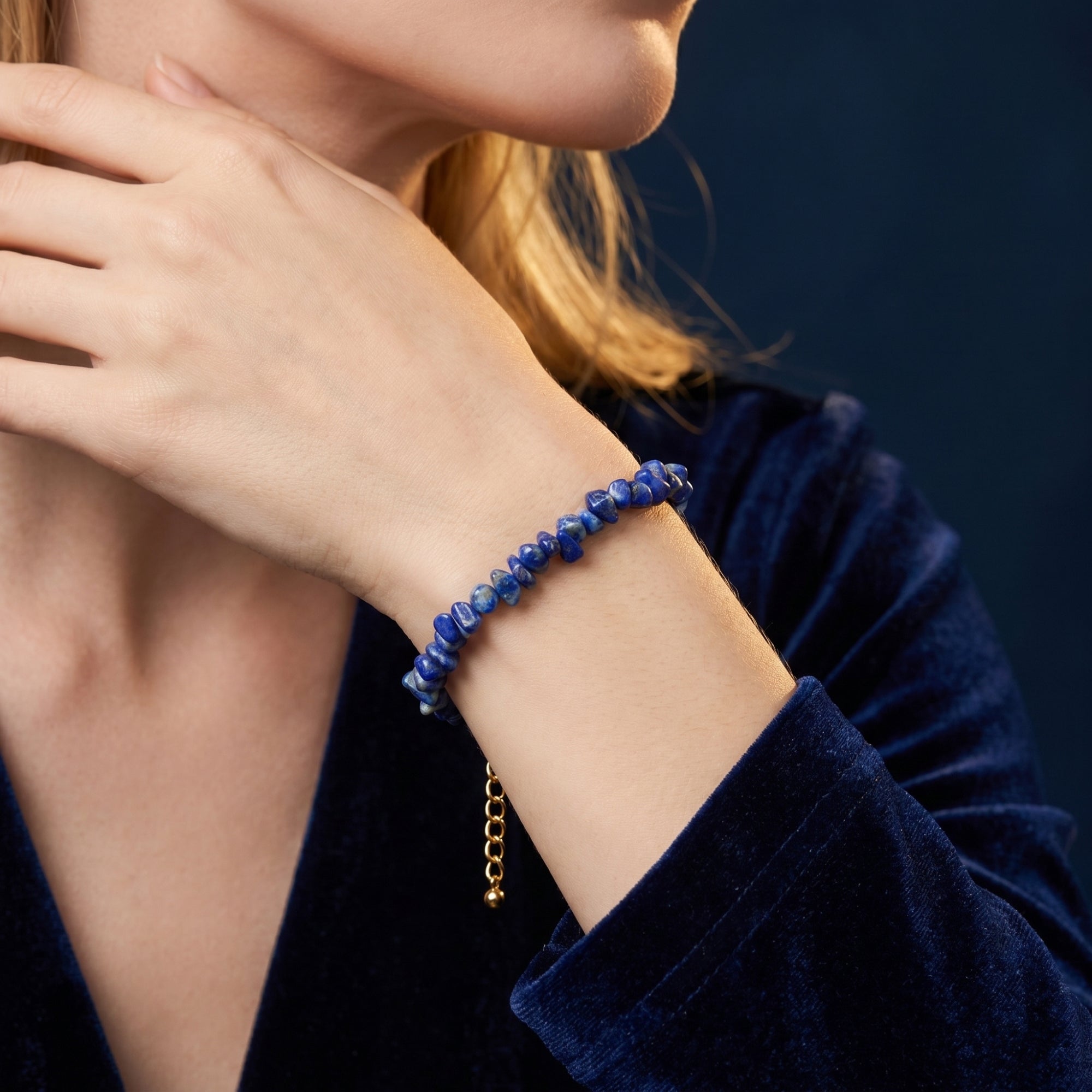 Blue lapis lazuli pebble bracelet with gold plated hardware styled on a model wearing blue velvet.