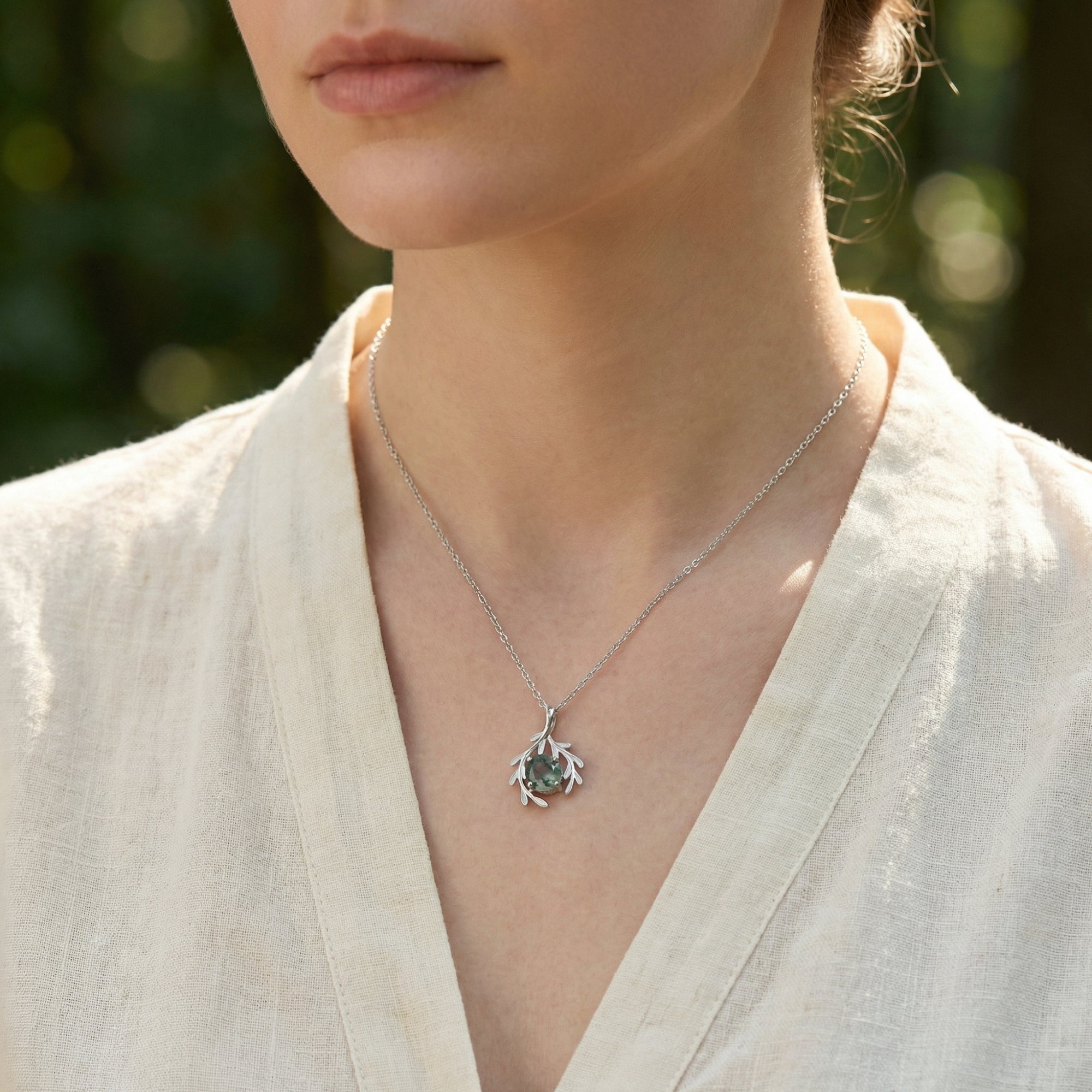 Close-up of a model wearing the sterling silver moss agate necklace, highlighting the delicate botanical pendant.